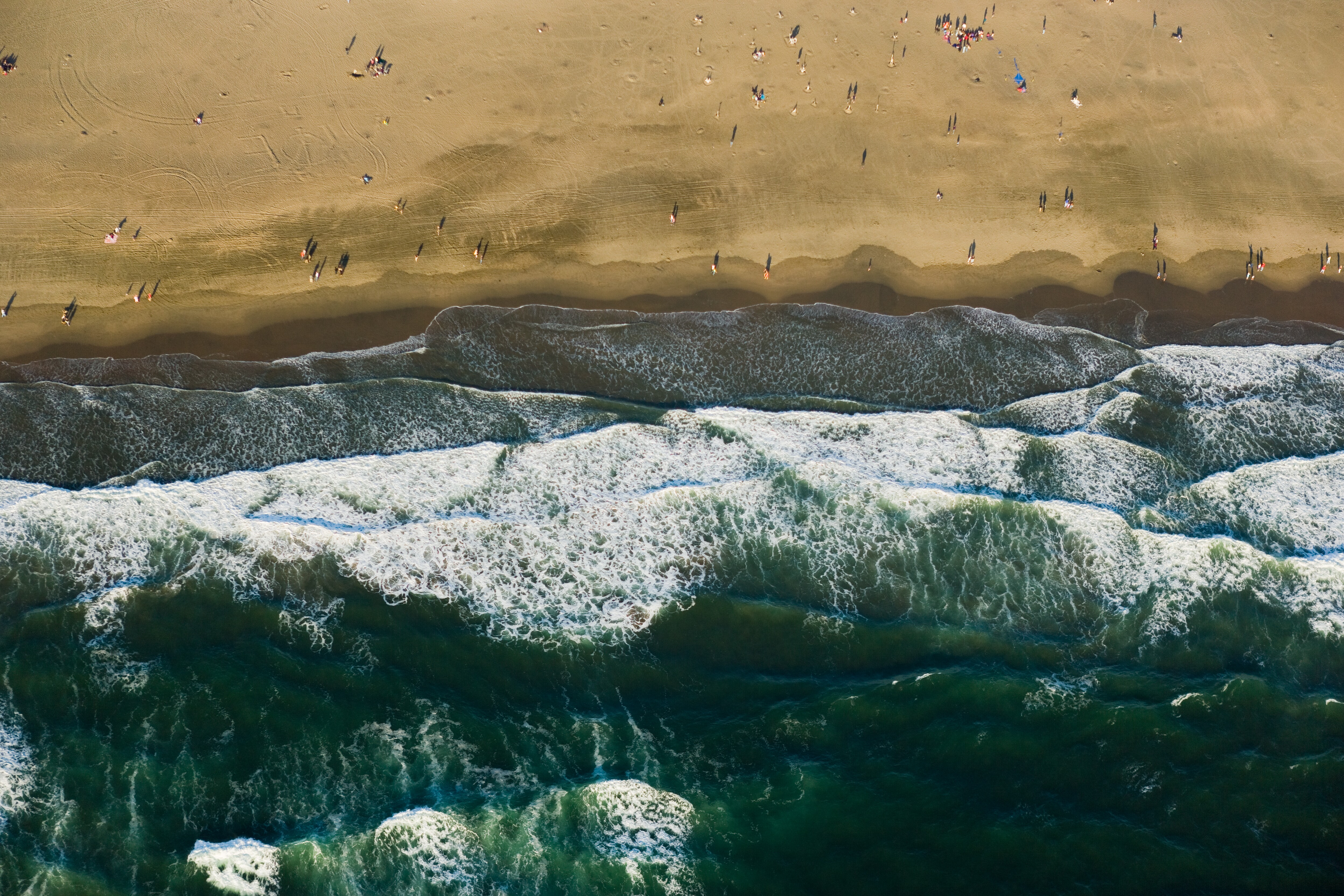 Overhead aerial image of the ocean meeting the beach shoreline.
