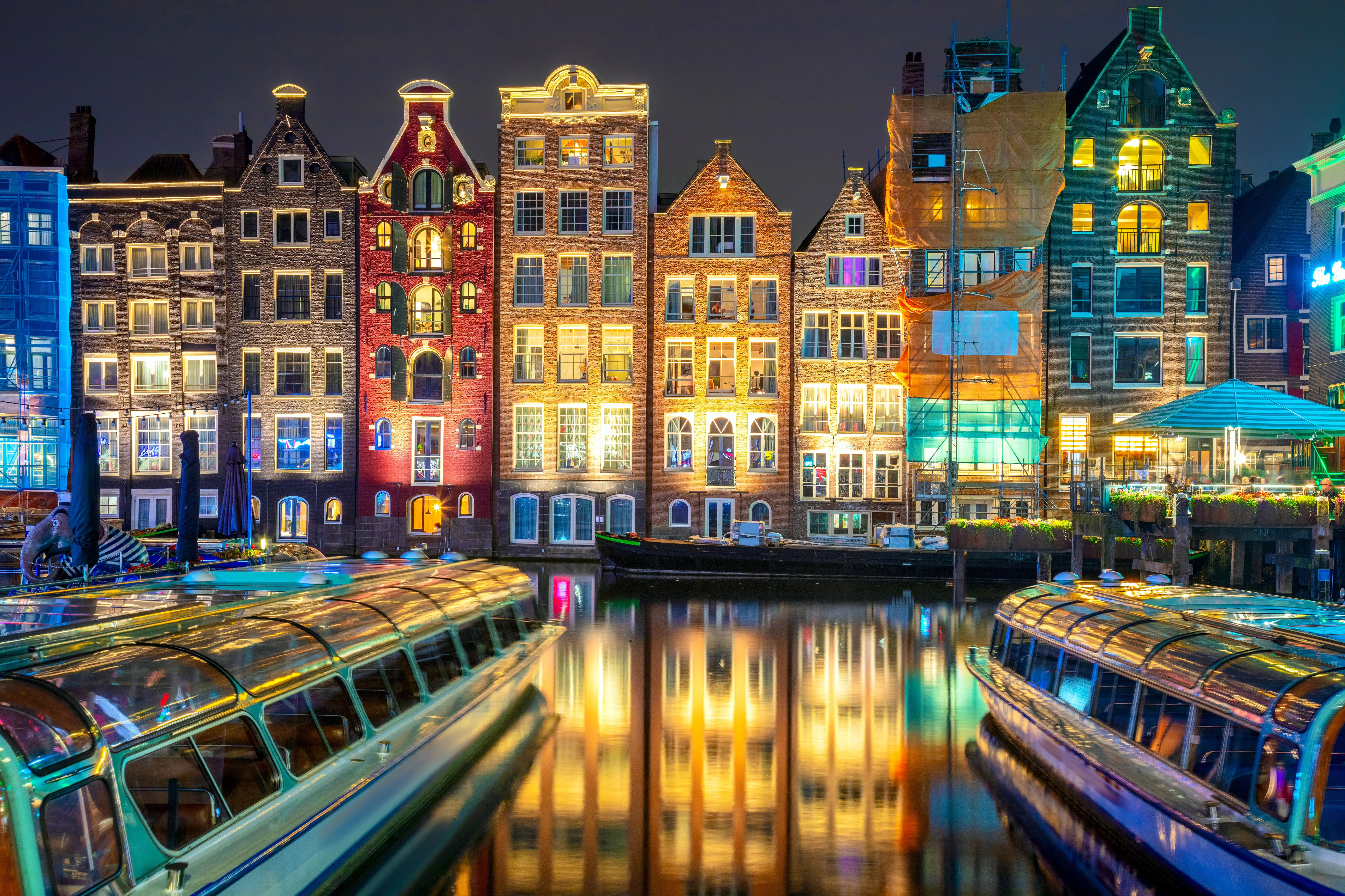 Damrak district with famous colorful old rowhouses in the canal in the evening