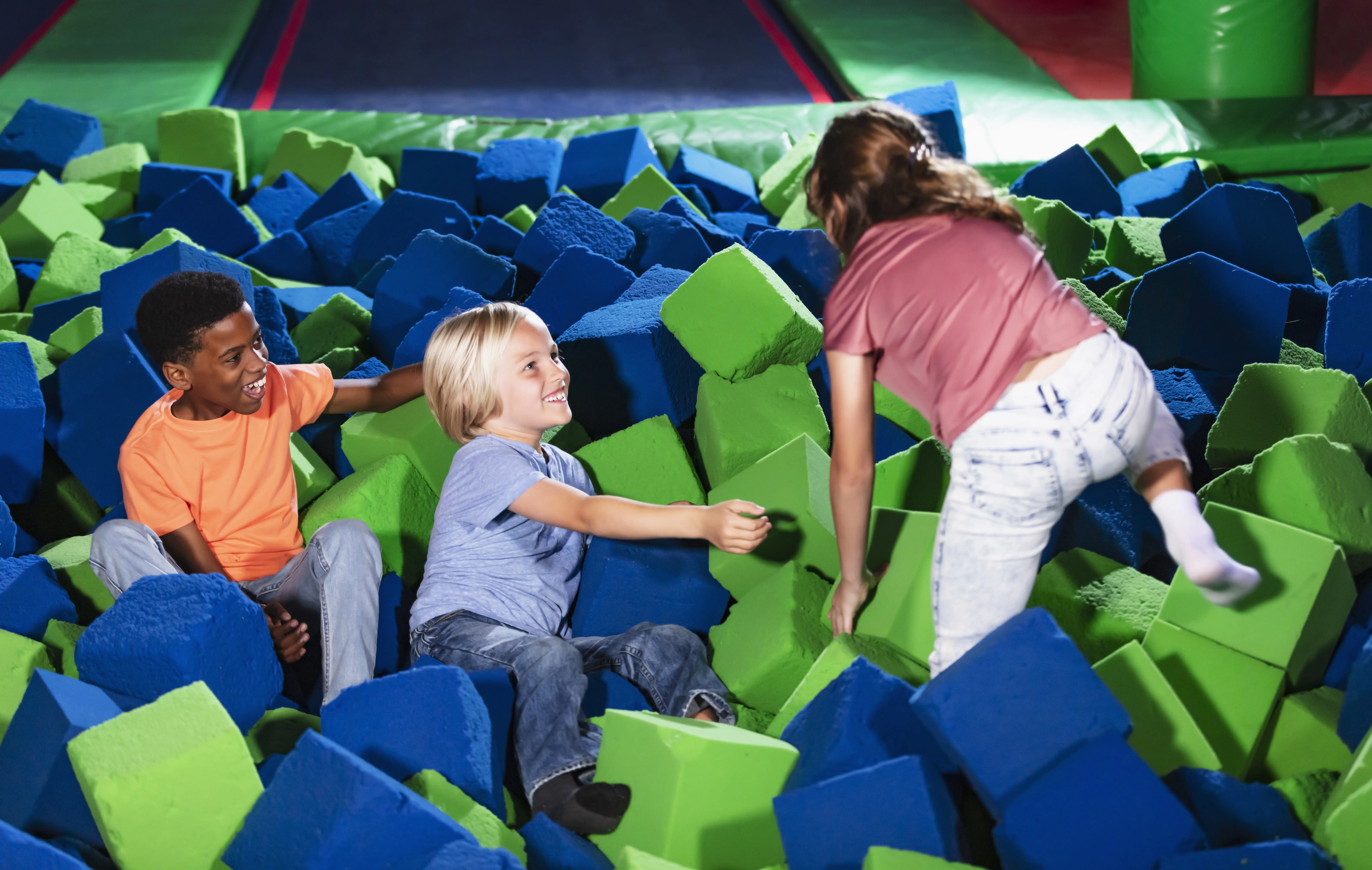 Image of three children playing in a pit of foam blocks.