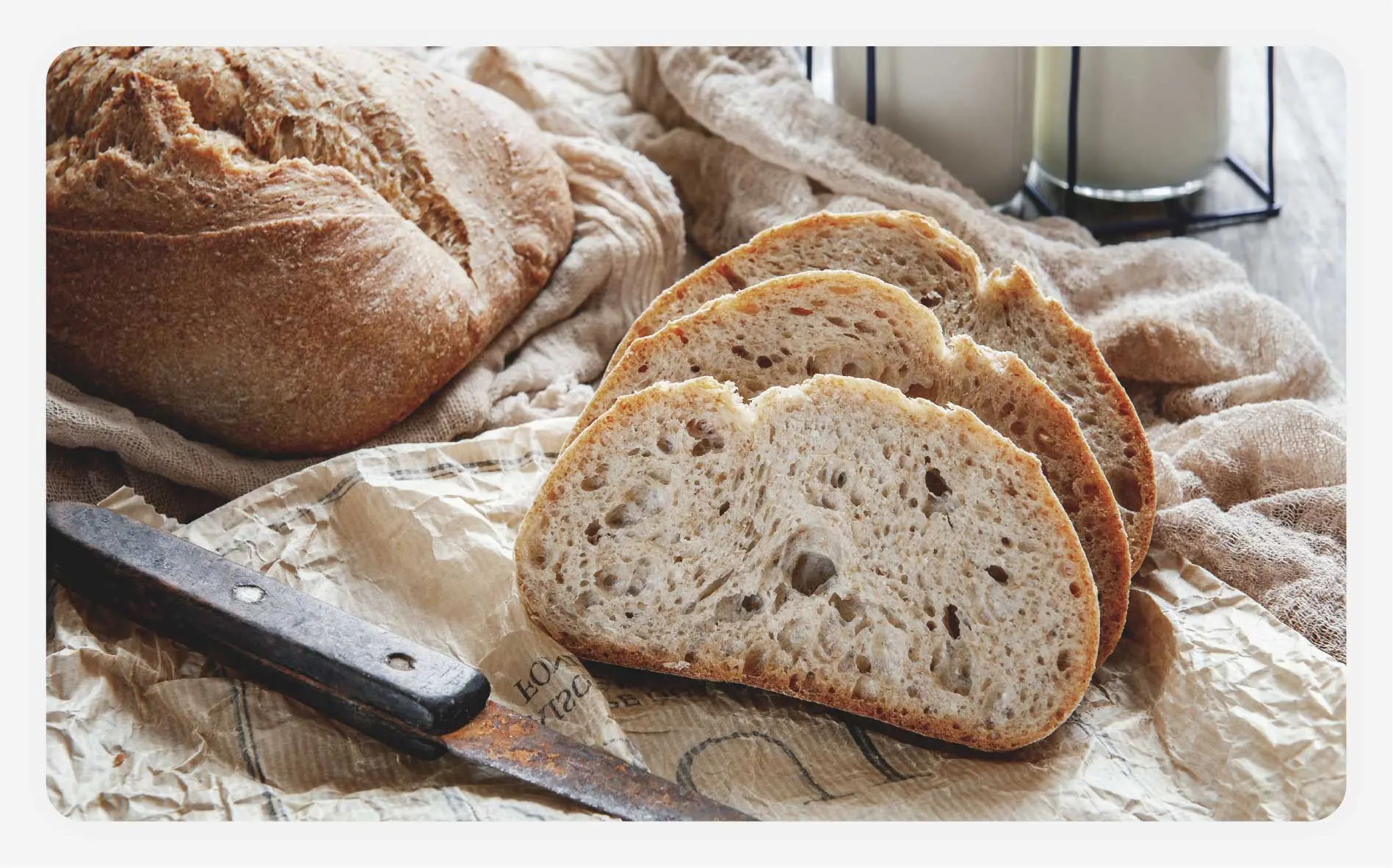 A sliced sourdough bread next to another bread loaf.