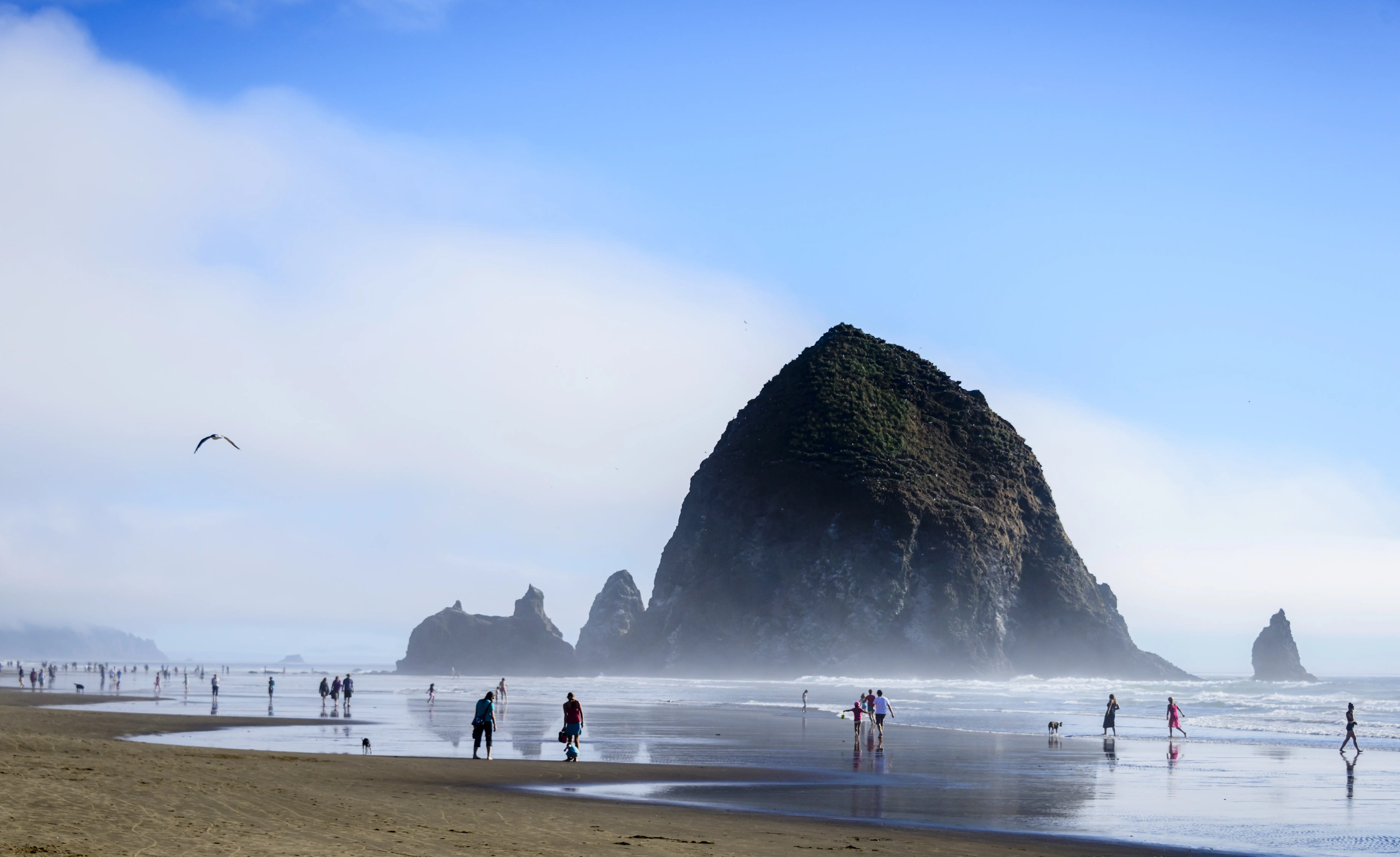 People enjoying a day at Cannon Beach with Haystack Rock in the background