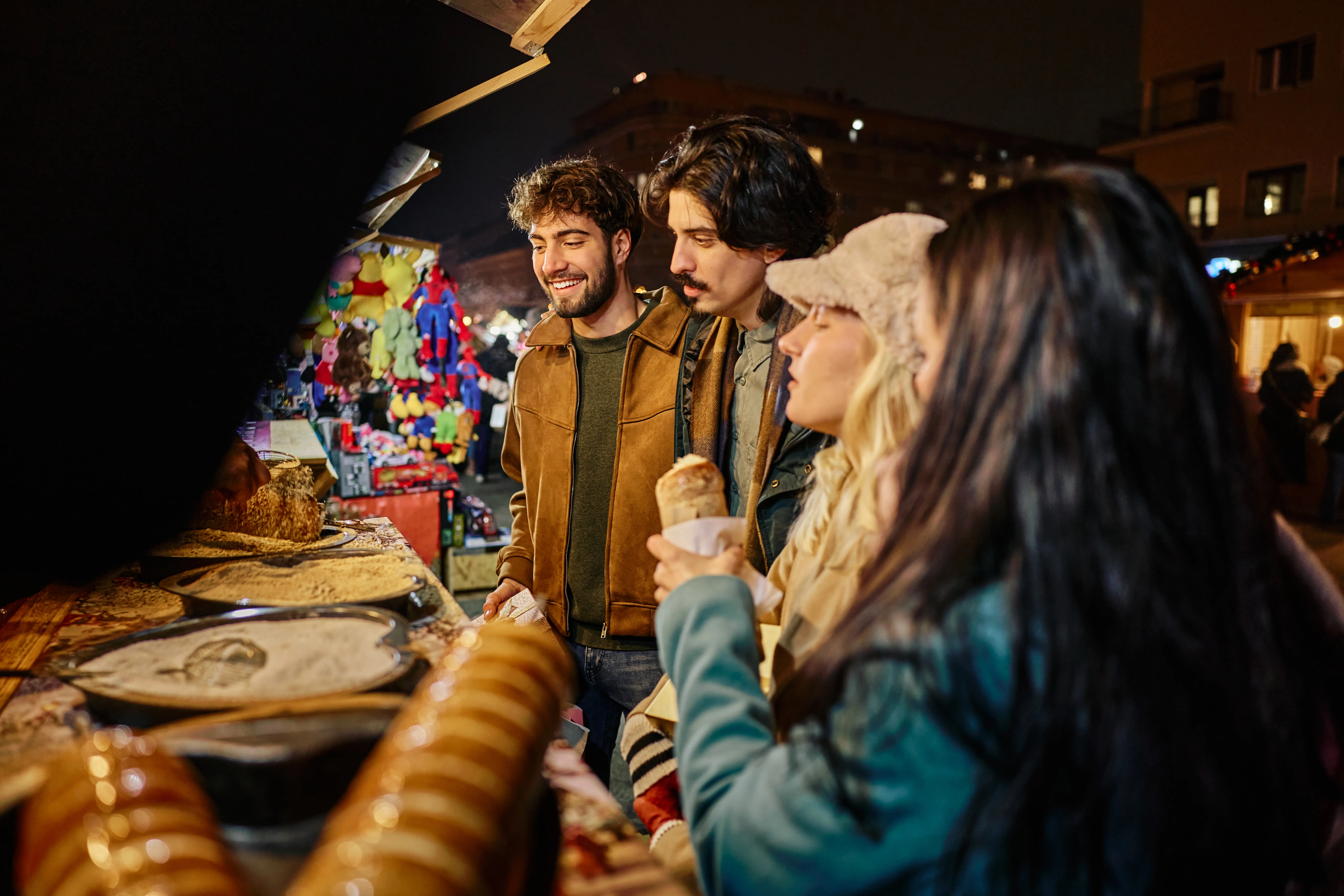 Image of a group of young adults exploring food and merchandise booths at a street fair.