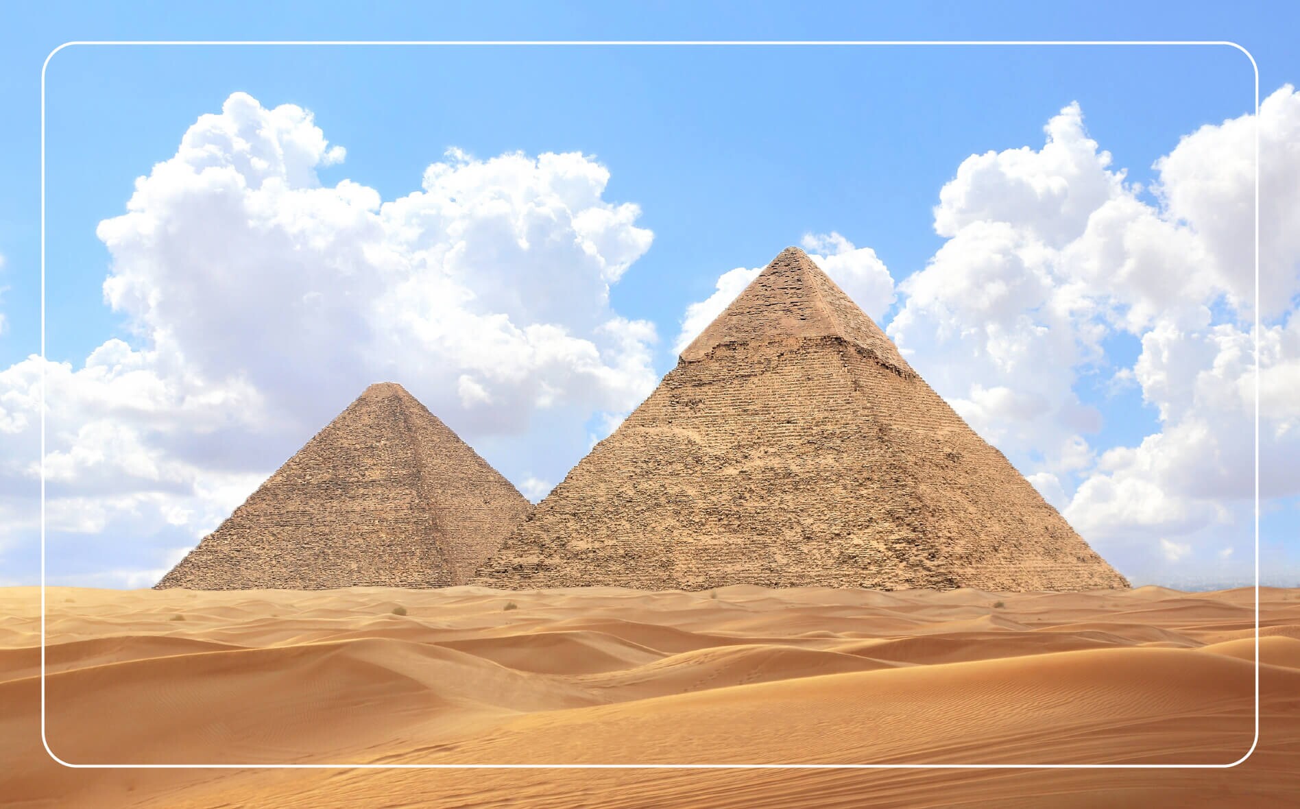 Two pyramids of Giza rising against a cloudy blue sky.