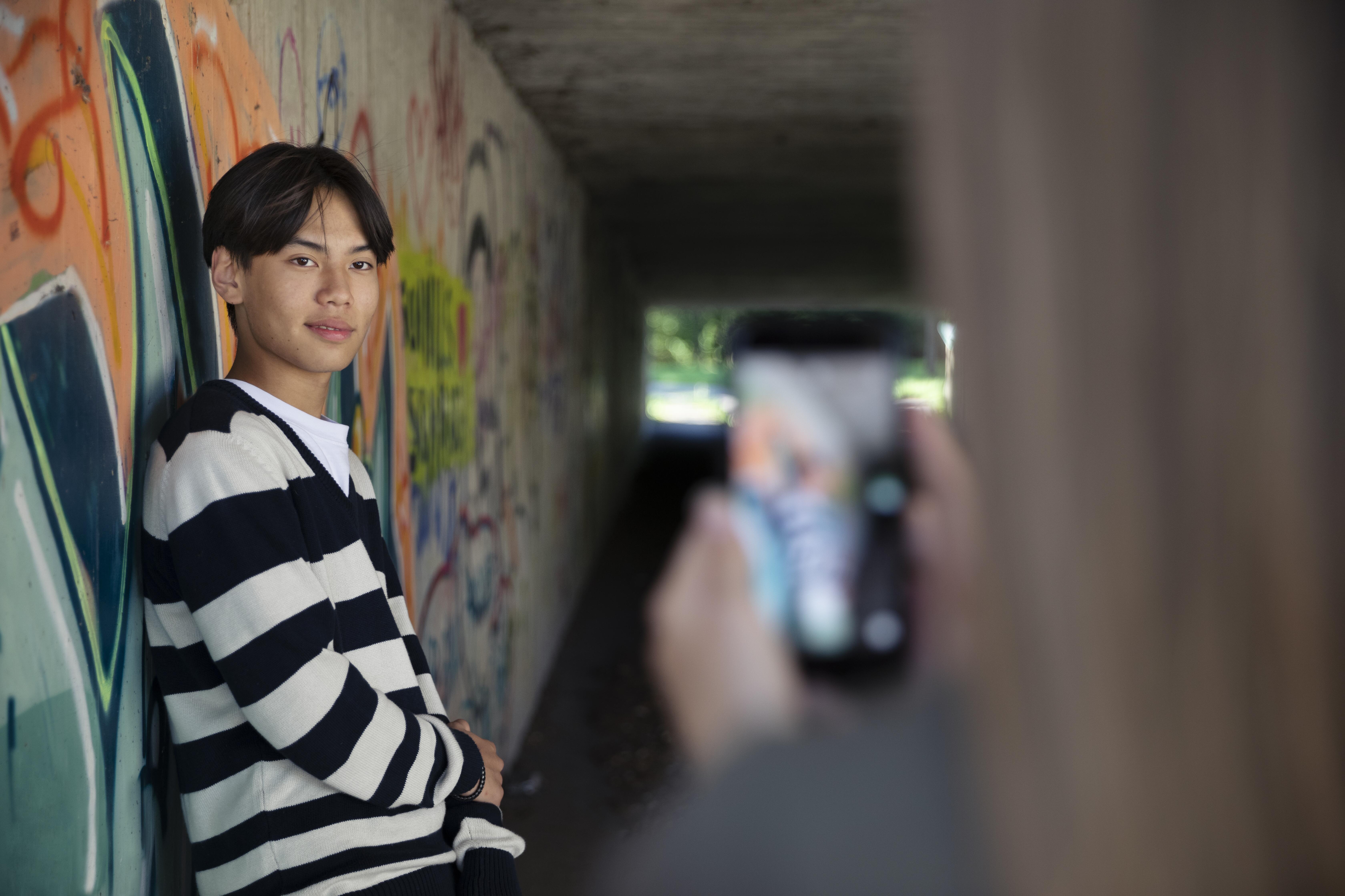 Image of a person posing for a photo in front of a colorful wall mural.