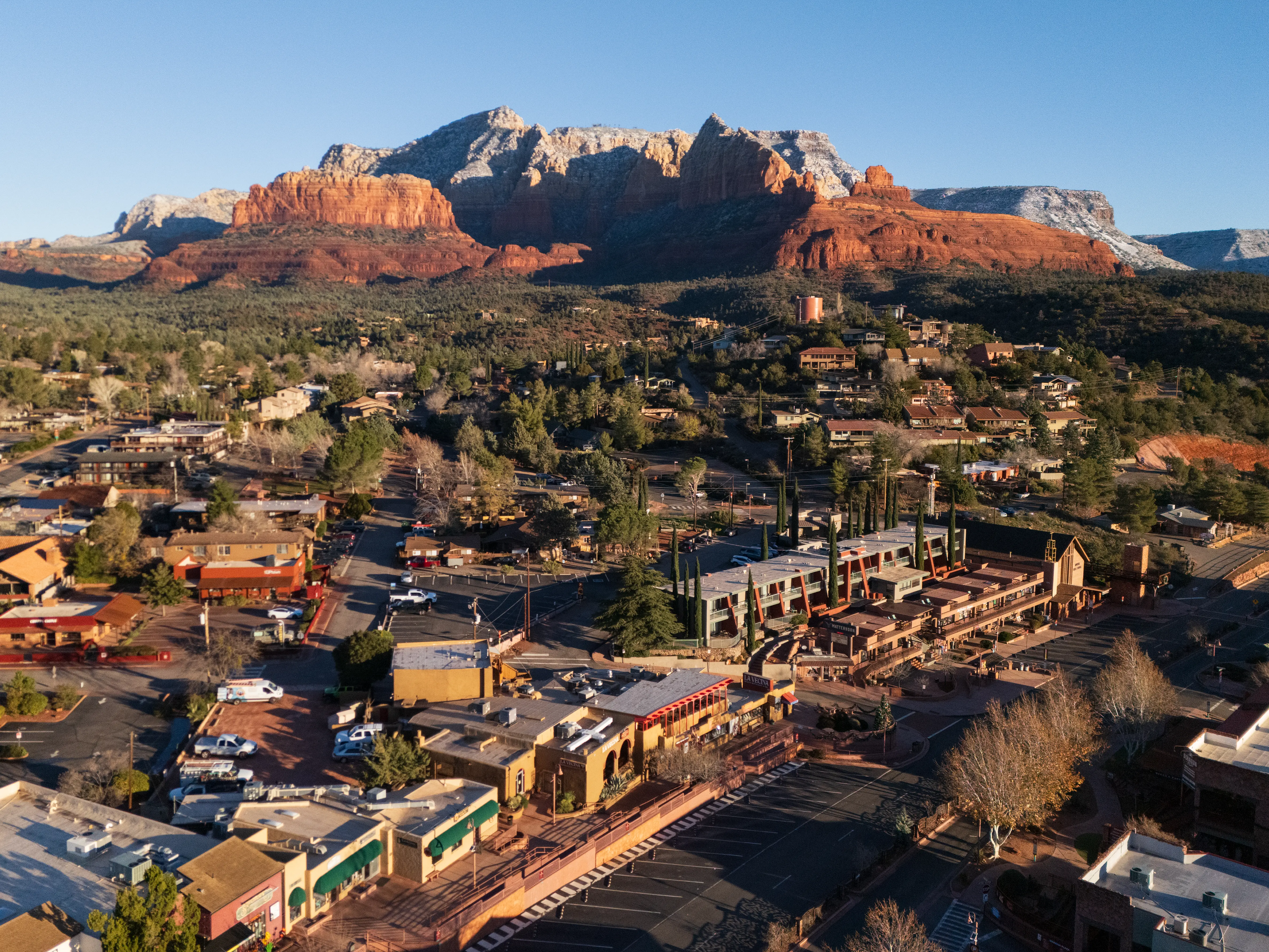 Aerial image of downtown Sedona, Arizona, with the red rocks its famous for visible in the background.
