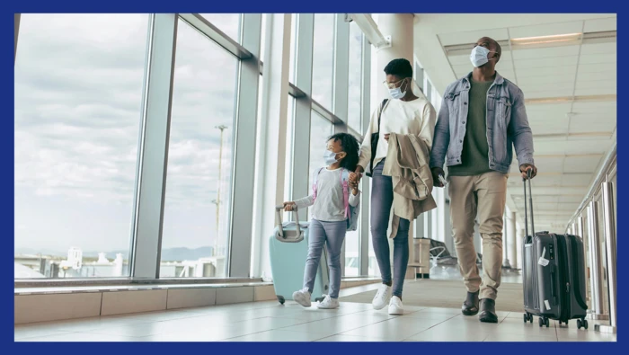 A family walking through the airport while wearing masks. 