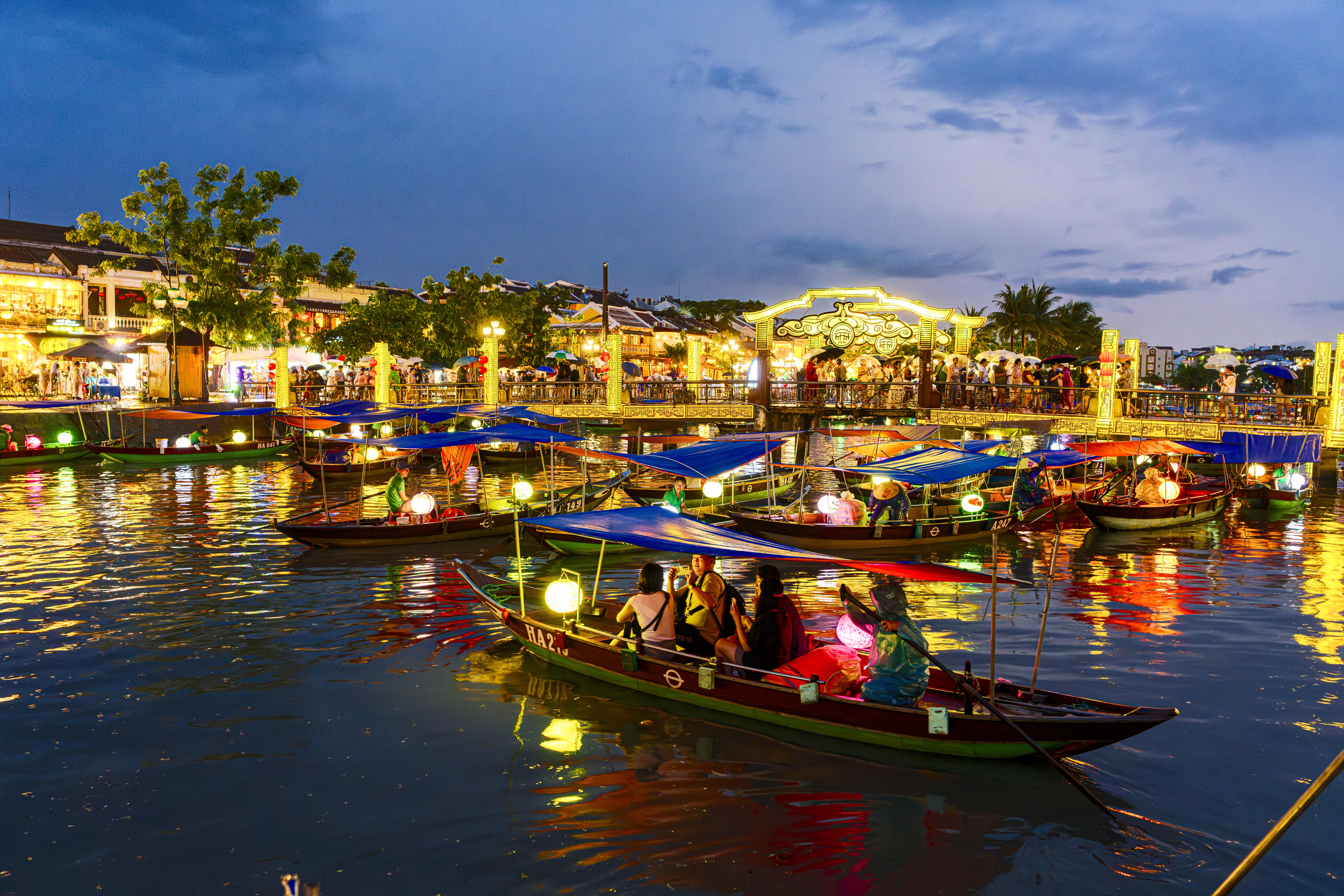 Image of a boat with tourists on Thu Bon River at dusk, Hoi An, Quang Nam Province, Vietnam.