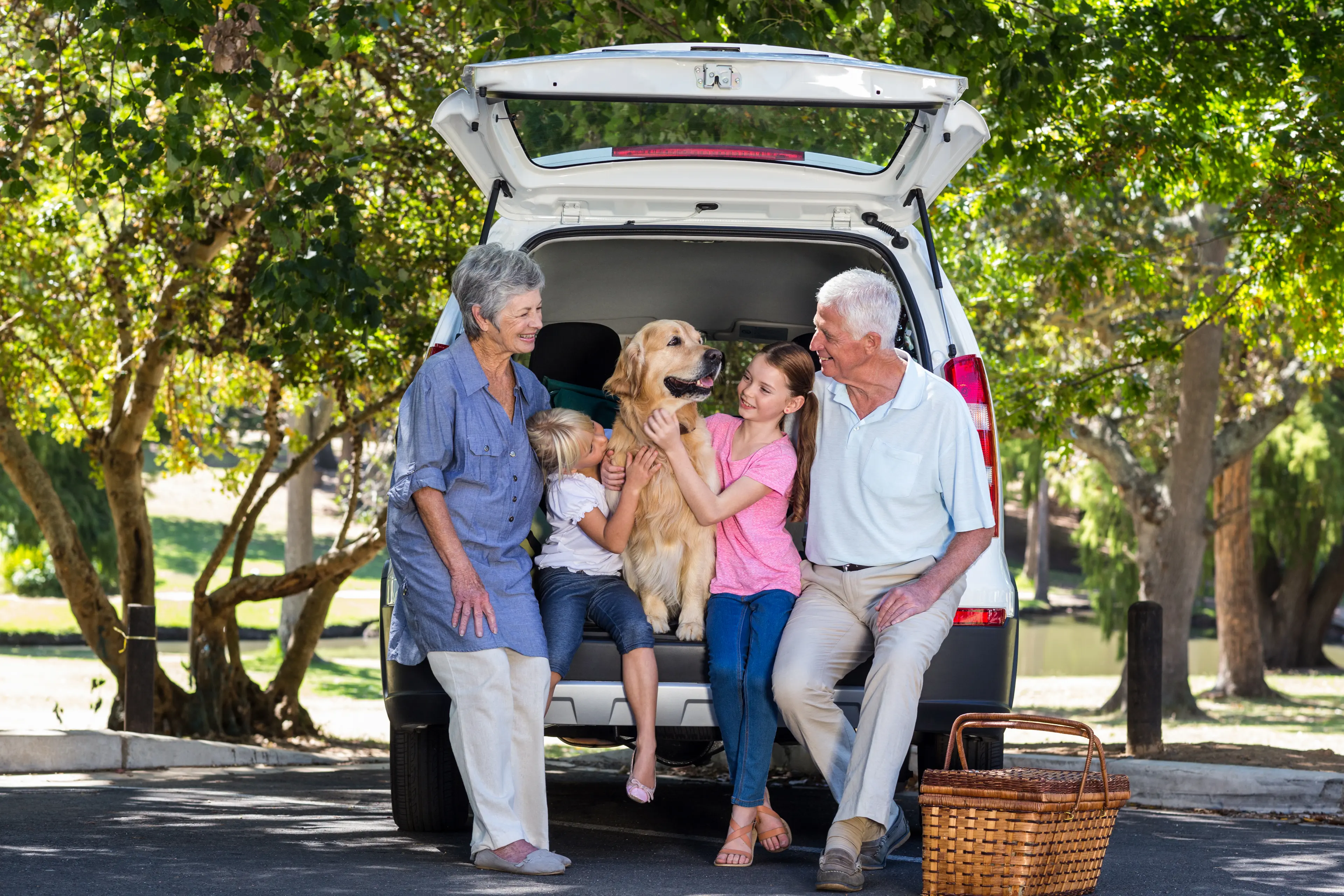 Family posing by car with a dog
