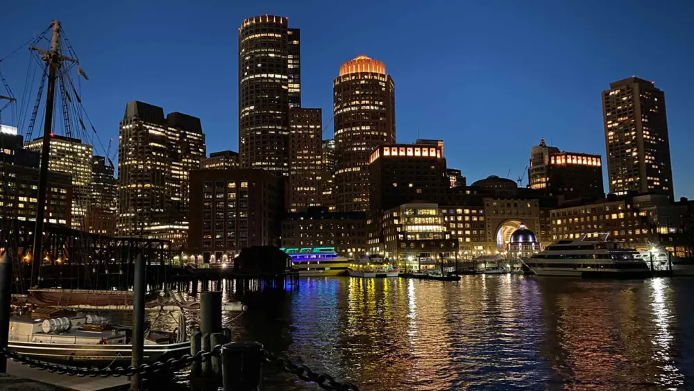 Night view of the Boston Harbor with Downtown Boston lit up in the background.