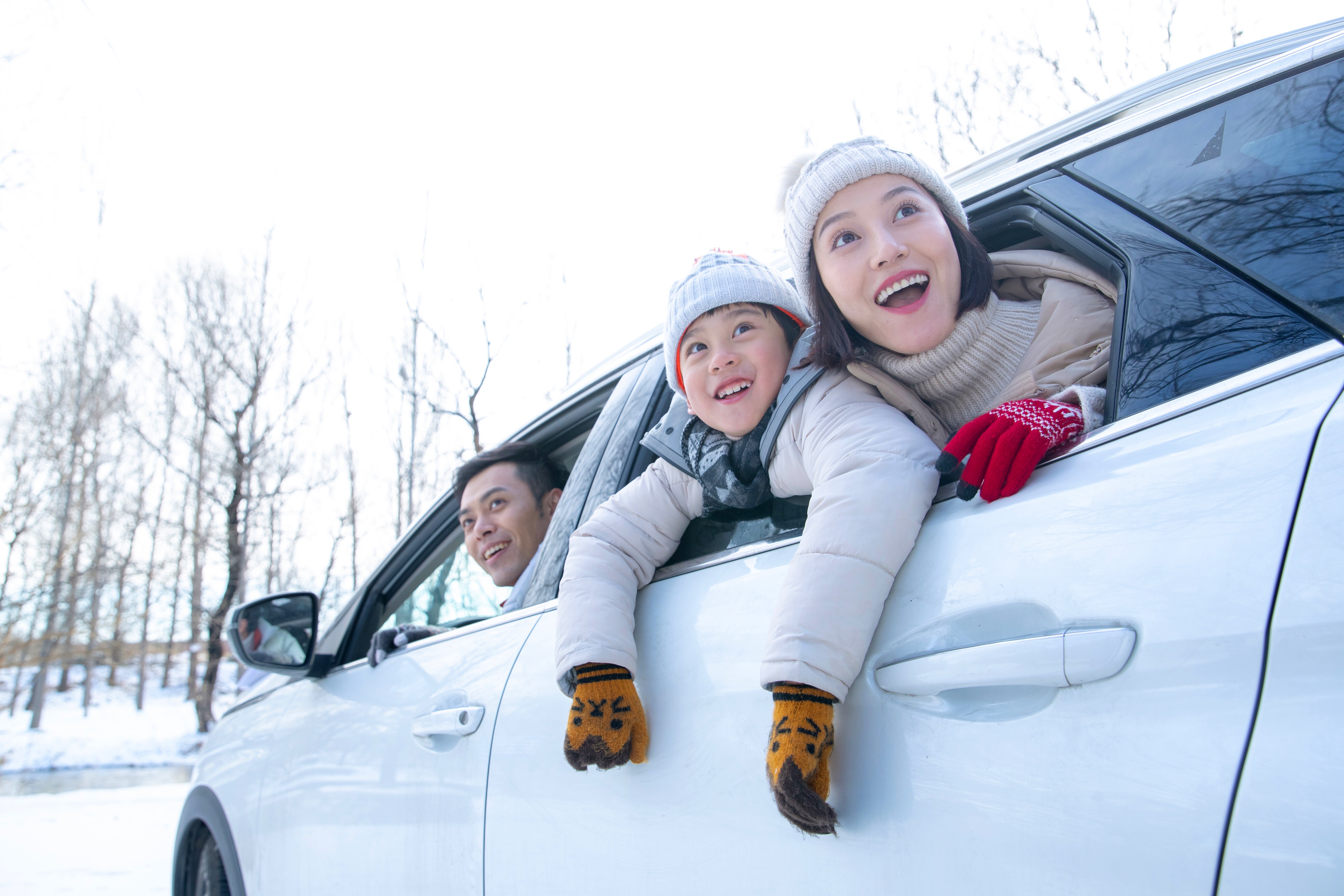 Family, dad, son, and daughter sitting in a white car sightseeing