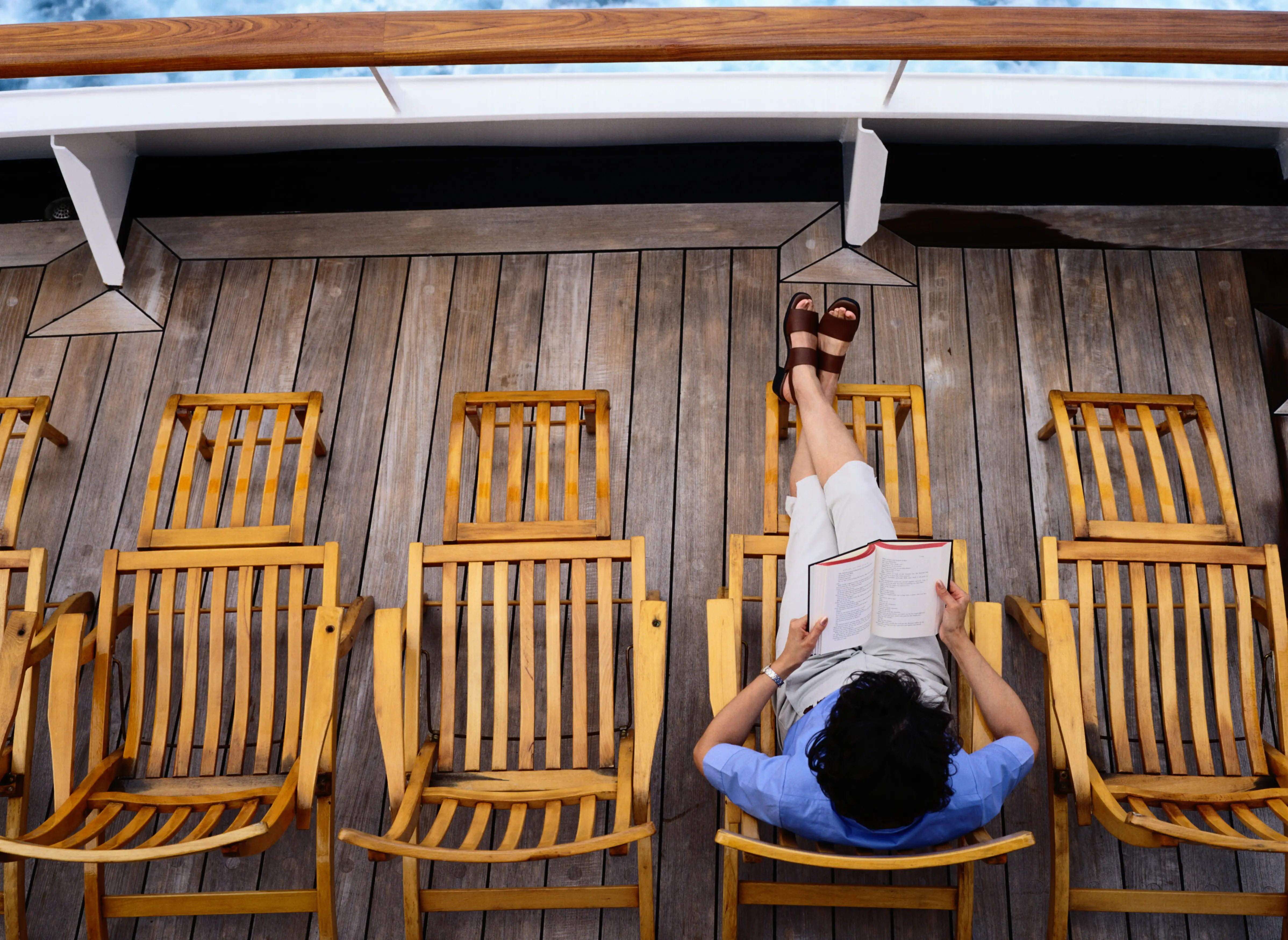 Image of a woman reading a book on the deck of a cruise ship.
