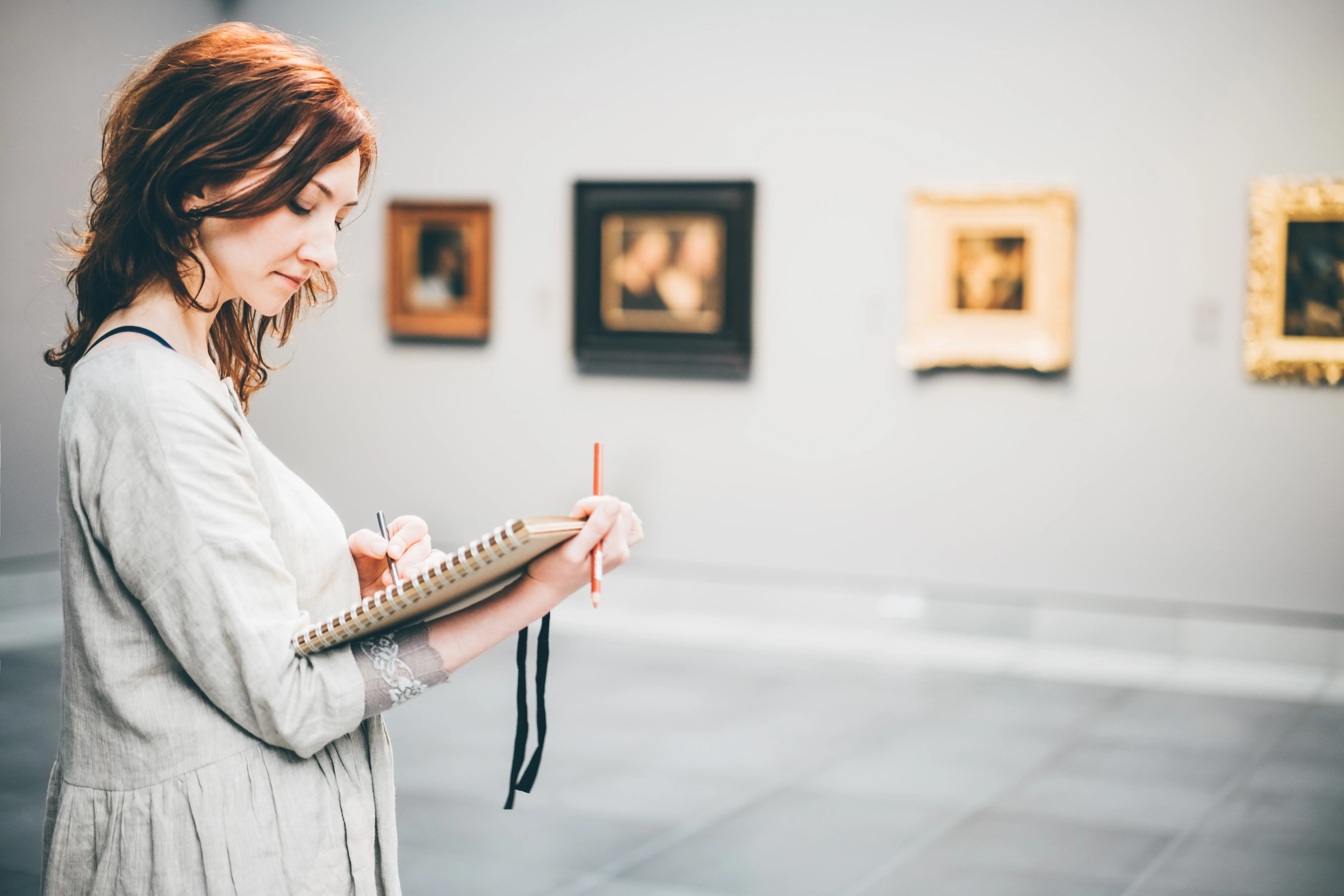 Image of a woman taking notes at an art museum.