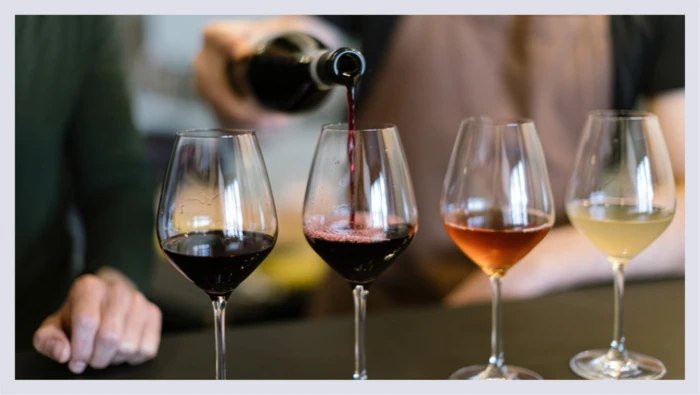 Four glasses of wine are lined up together while wine is poured into them for a wine tasting. 