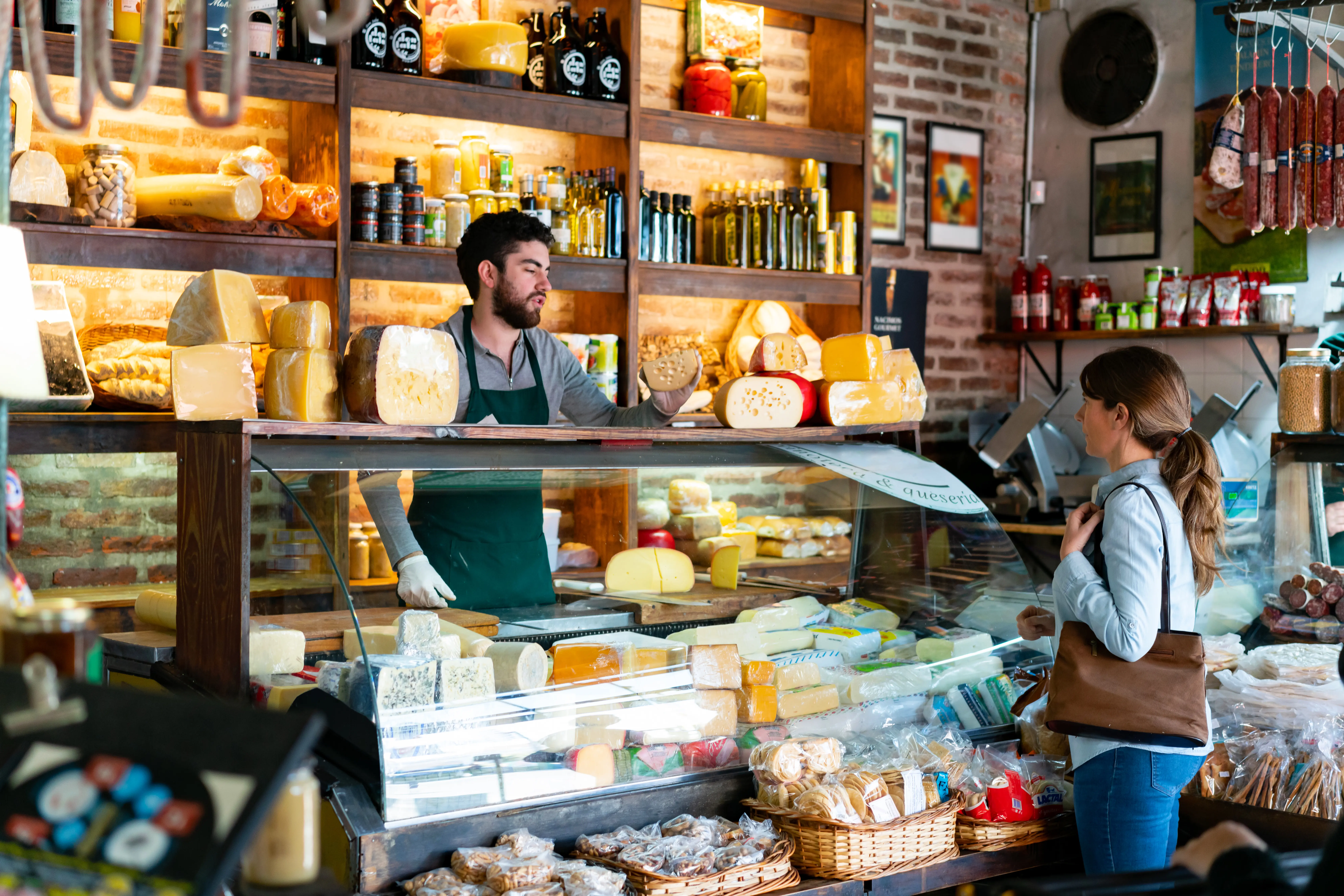 Cheese monger suggesting artisanal cheeses to a female customer