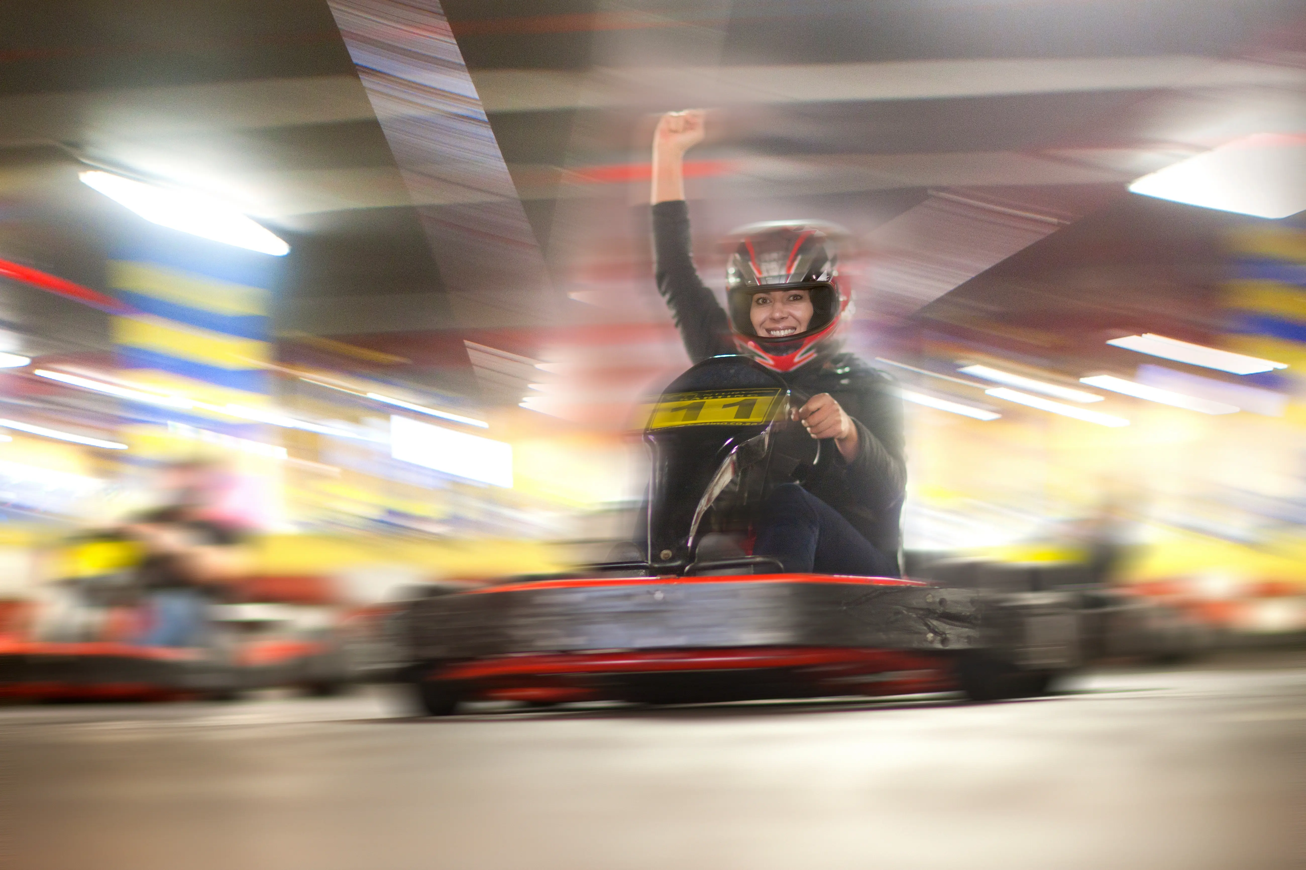 Image of a woman riding a go kart on an indoor track.