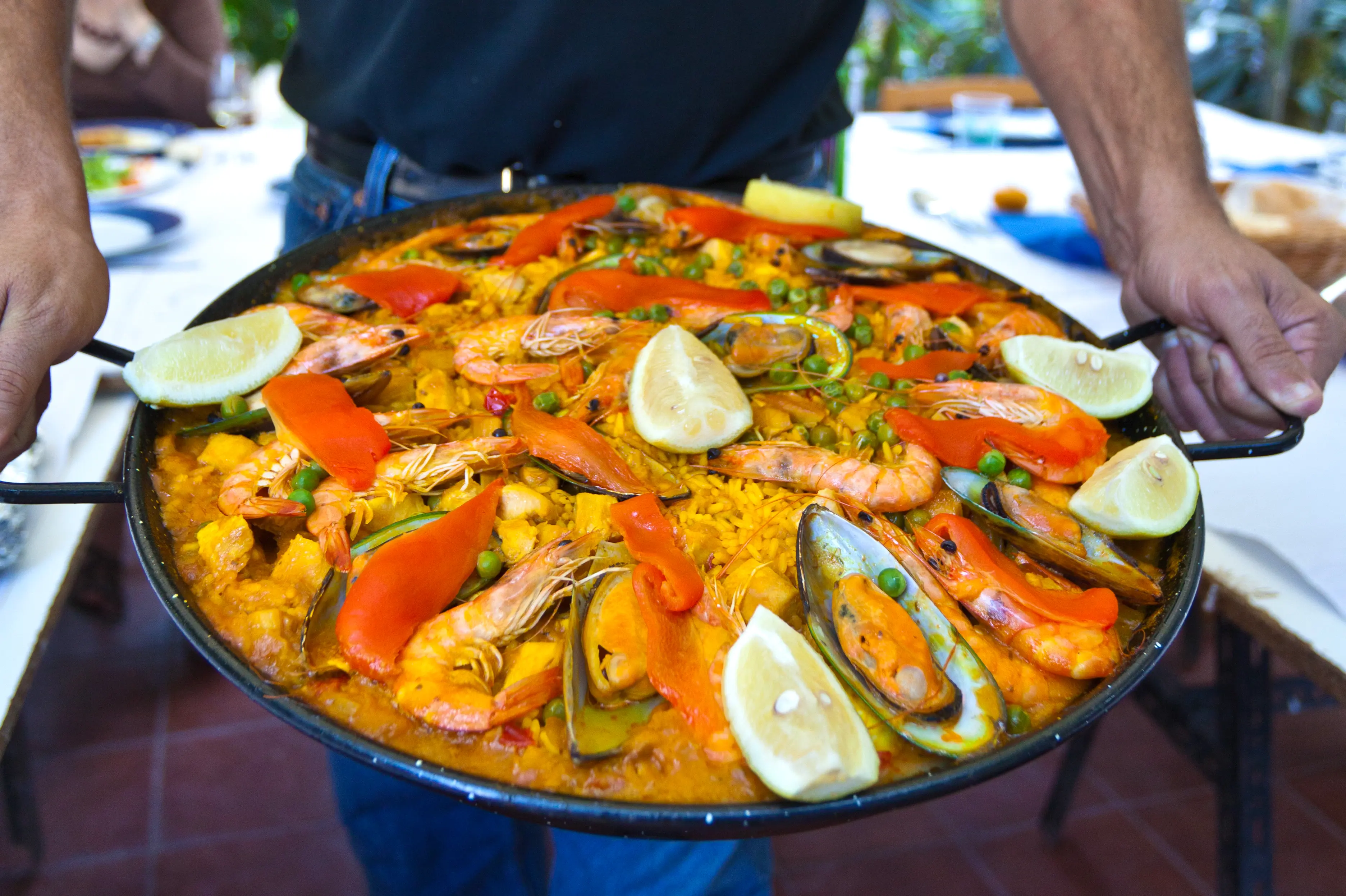Man holding a large pan of seafood paella