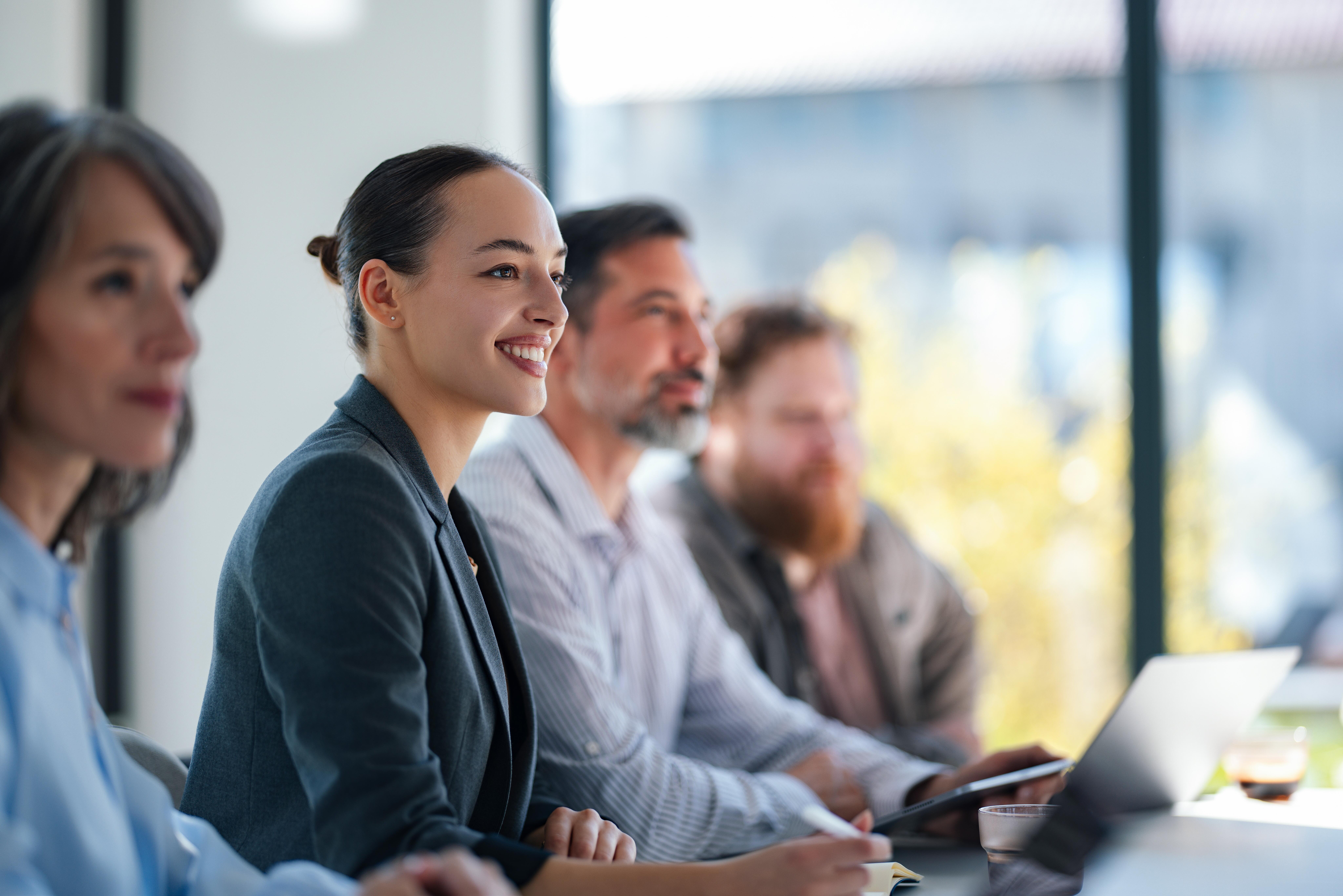 Image of a woman smiling during a business meeting in an office setting.