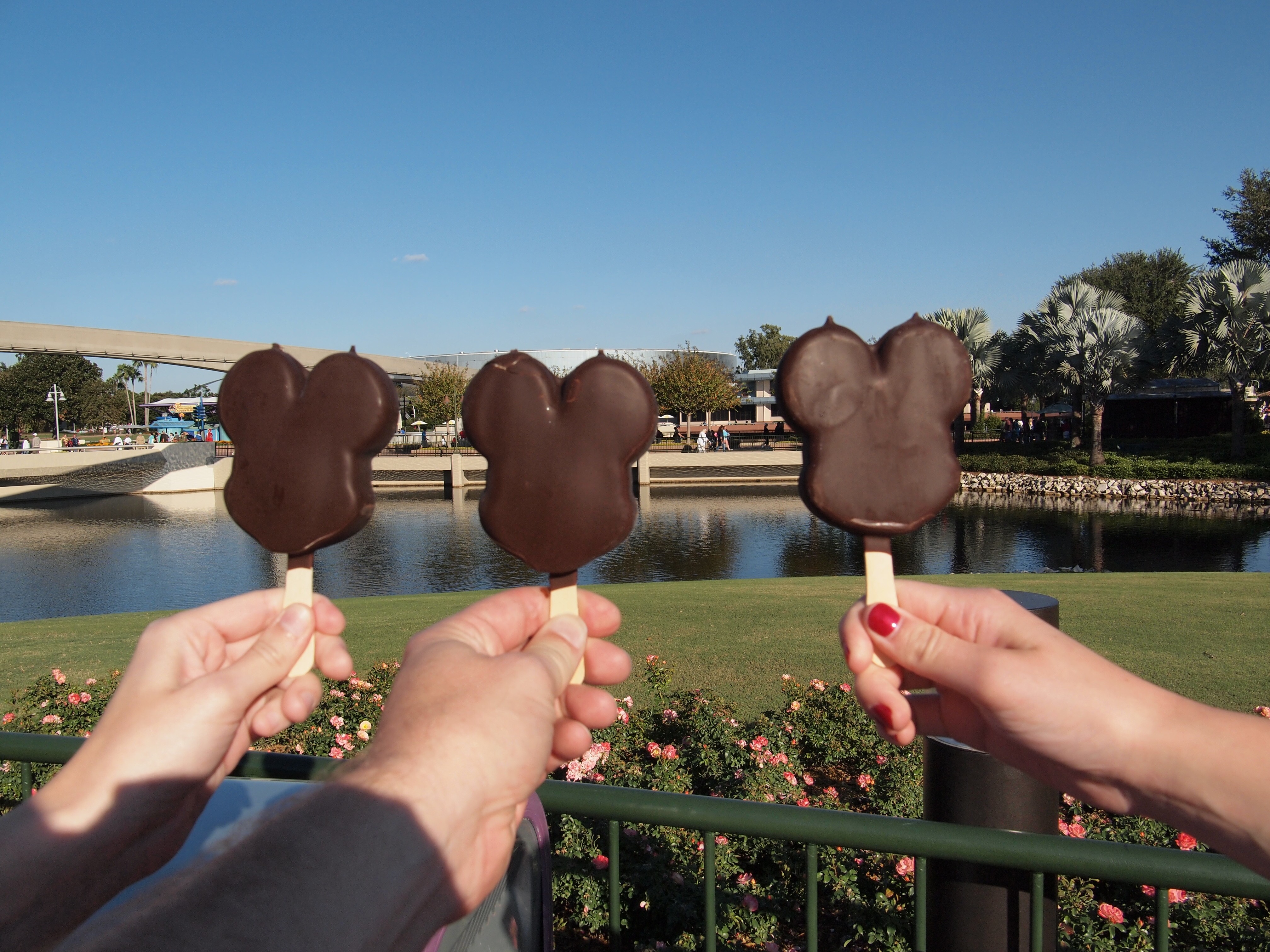 Image of three people holding up Mickey Ice Cream bars at Epcot.