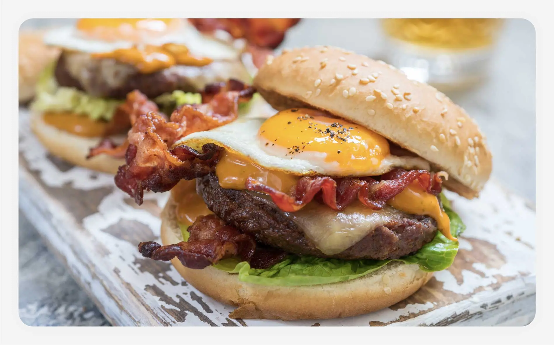 Several American-style burgers with a sunny-side egg and bacon