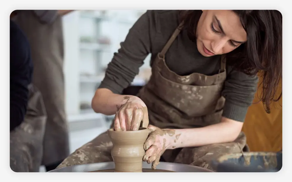 Young woman artist making clay bowl on pottery wheel