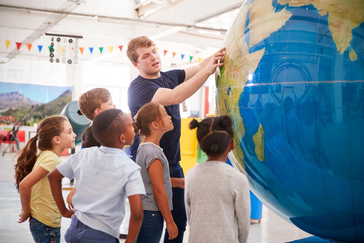 Kids watch presentation with giant globe at a science center.