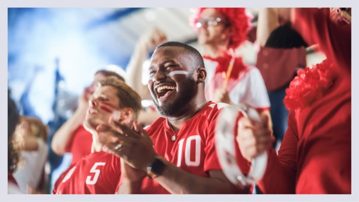 Sports fans are shown cheering on a team in the crowd. 