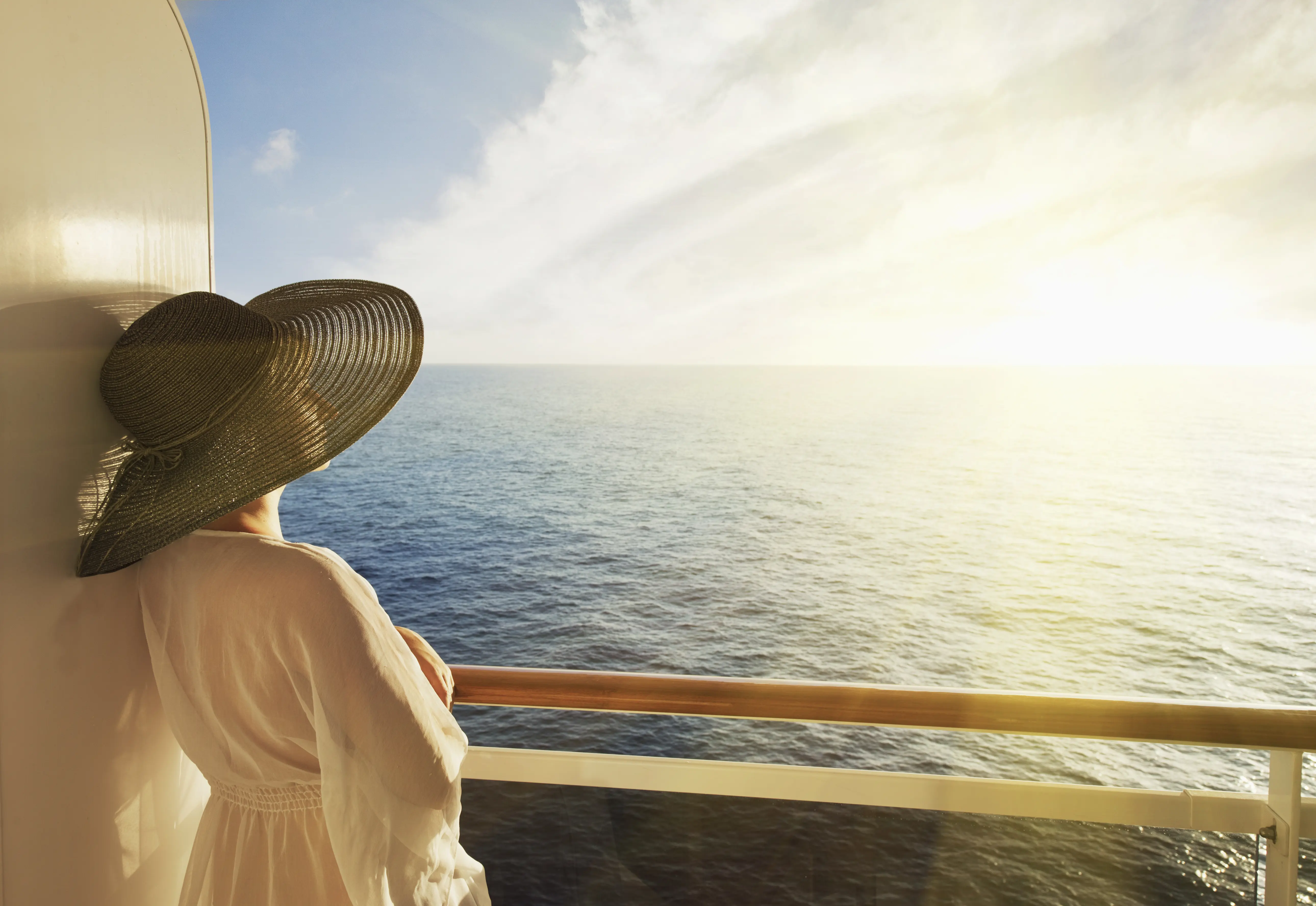 Woman looking at sunset from cruise ship balcony