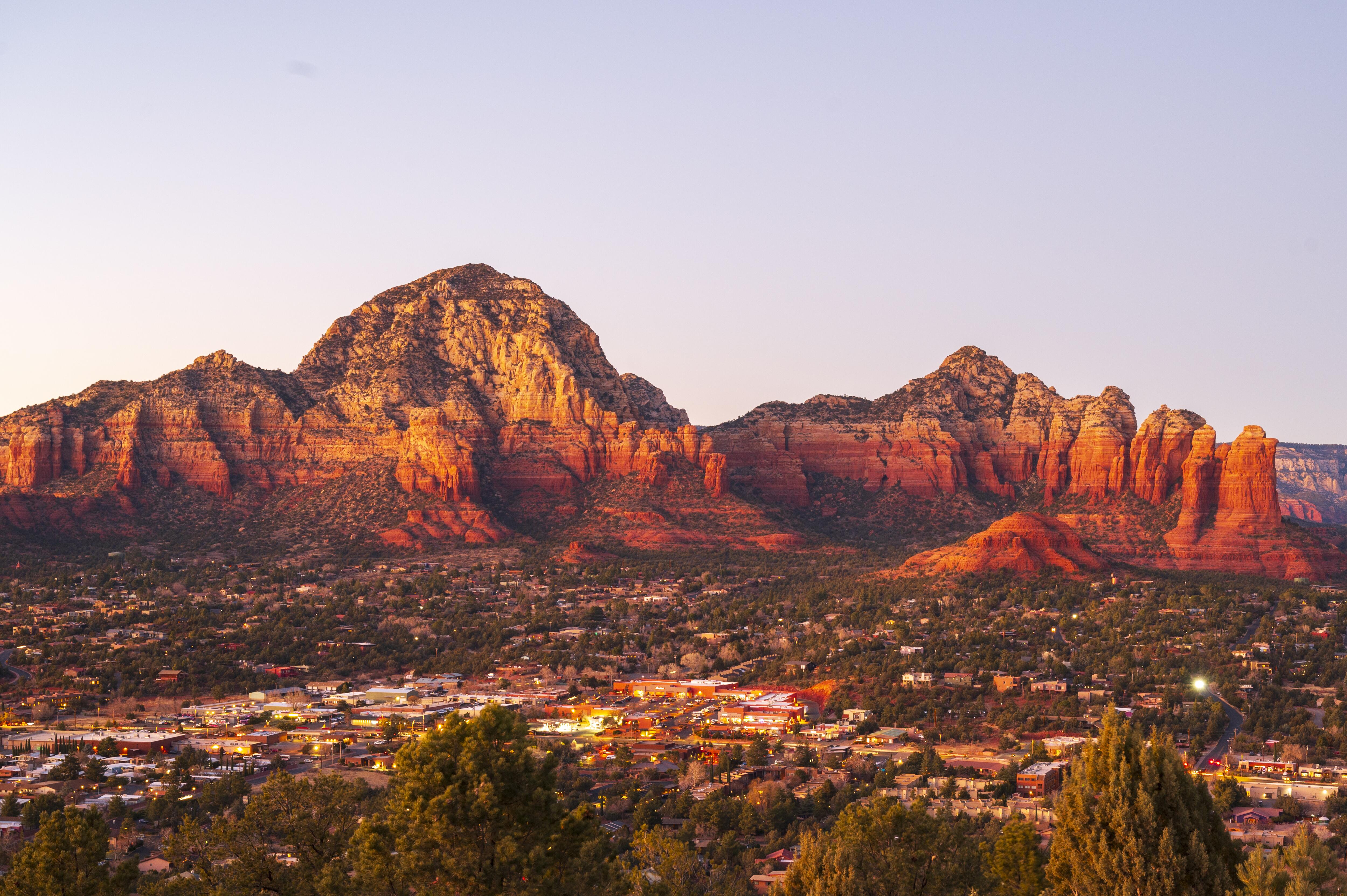 Image of the town of Sedona, Arizona and its surrounding rock formations, taken at dusk.