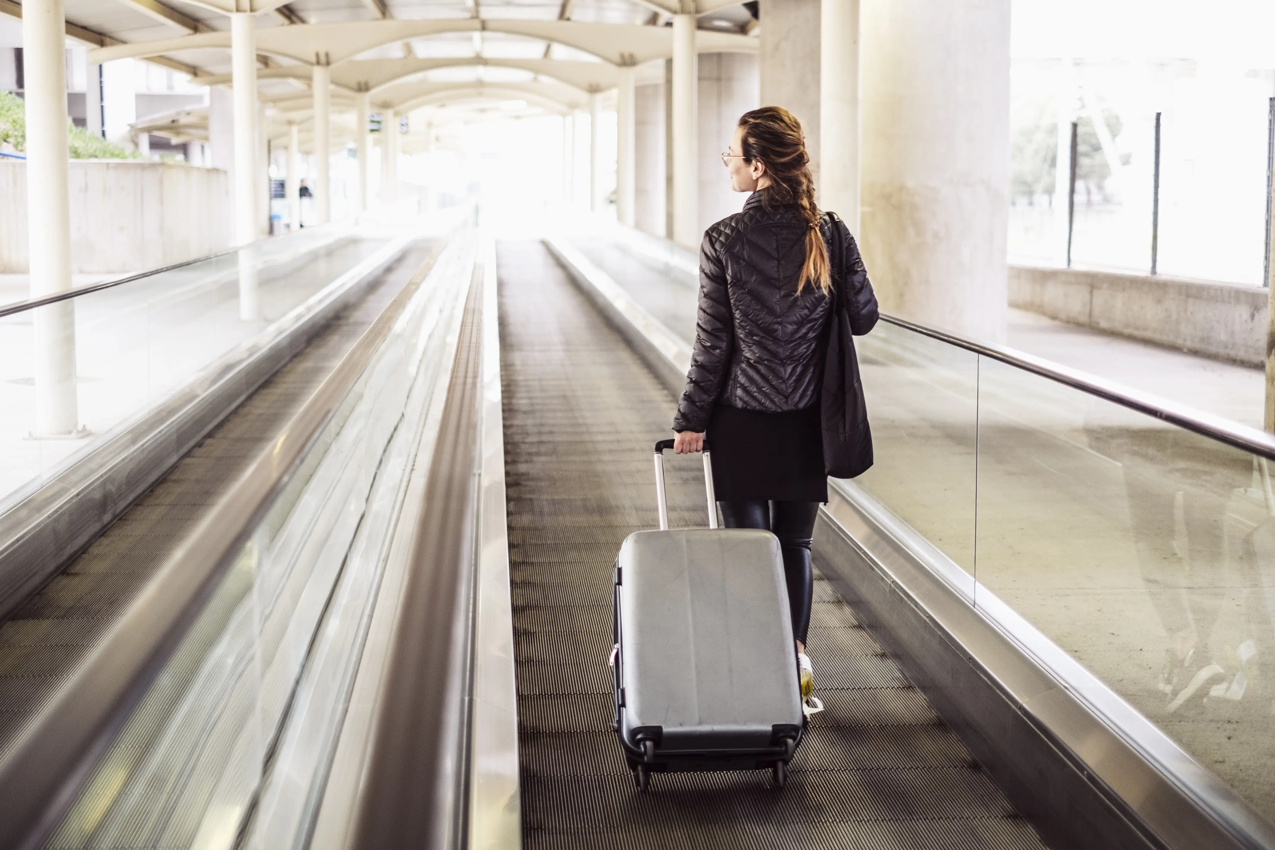 Lady on airport people moving with her luggage