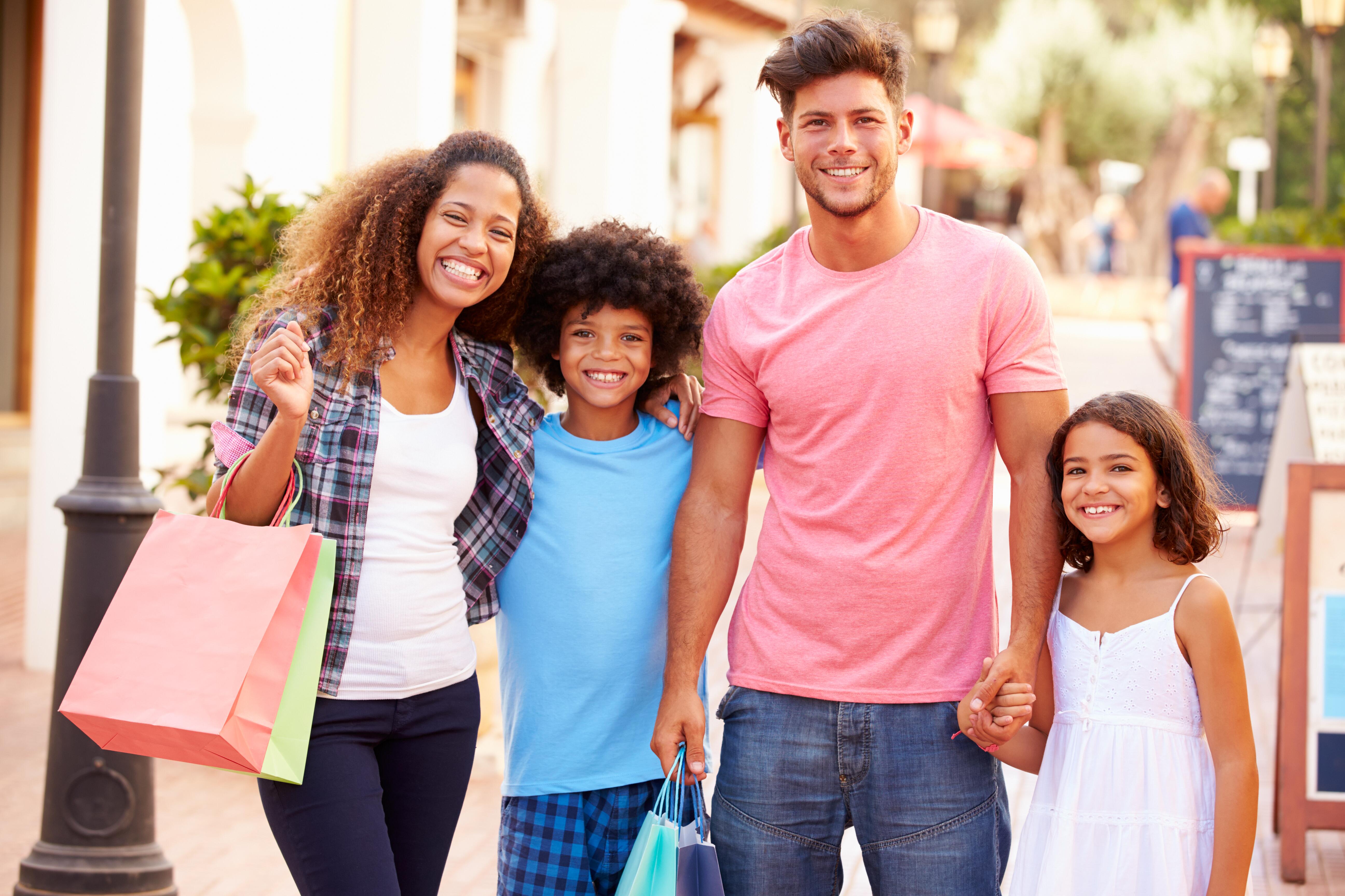 Portrait of mixed race family walking in outdoor plaza with shopping bags