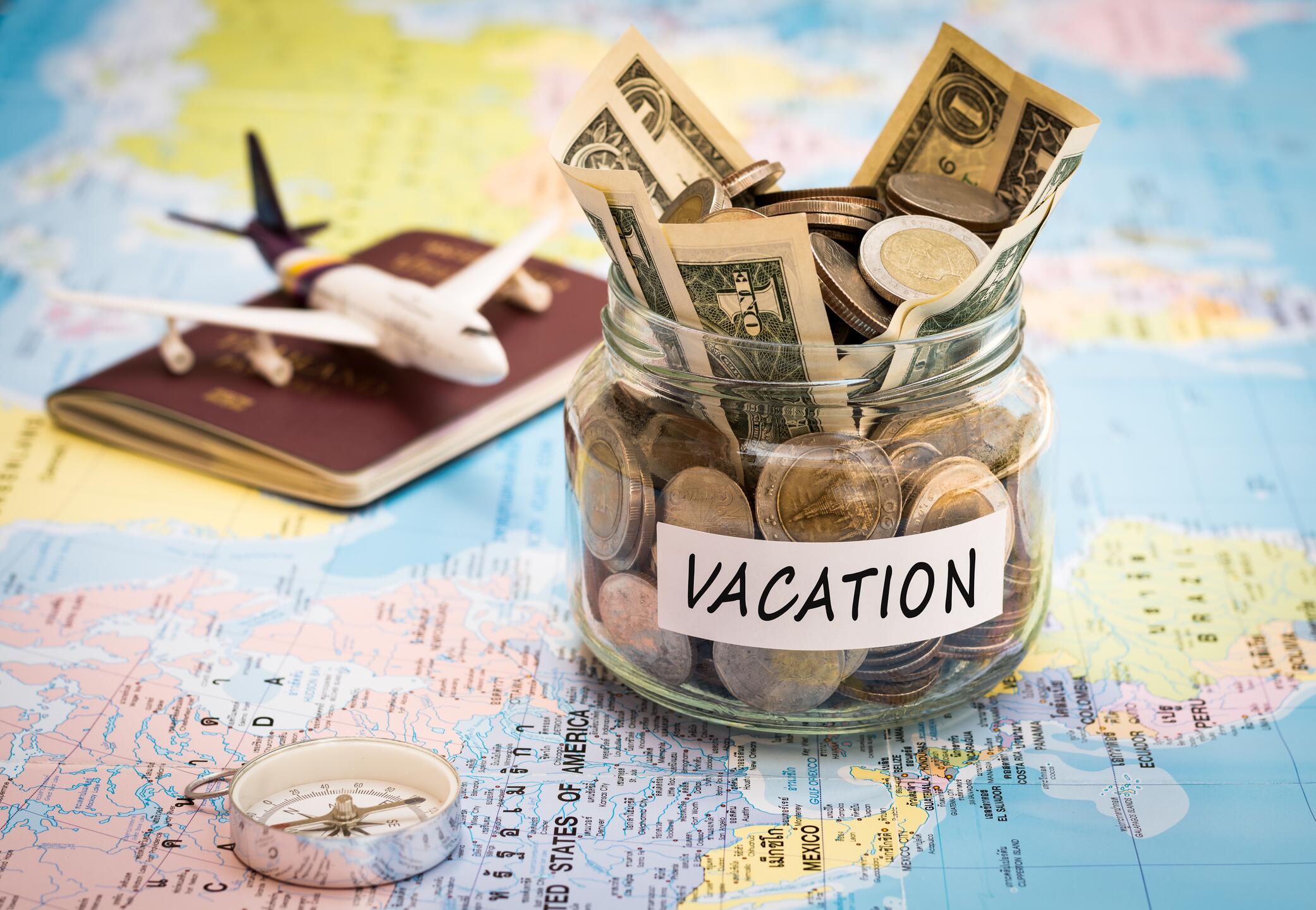 Photo of map, toy airplane, jar of dollar bills and coins, passport