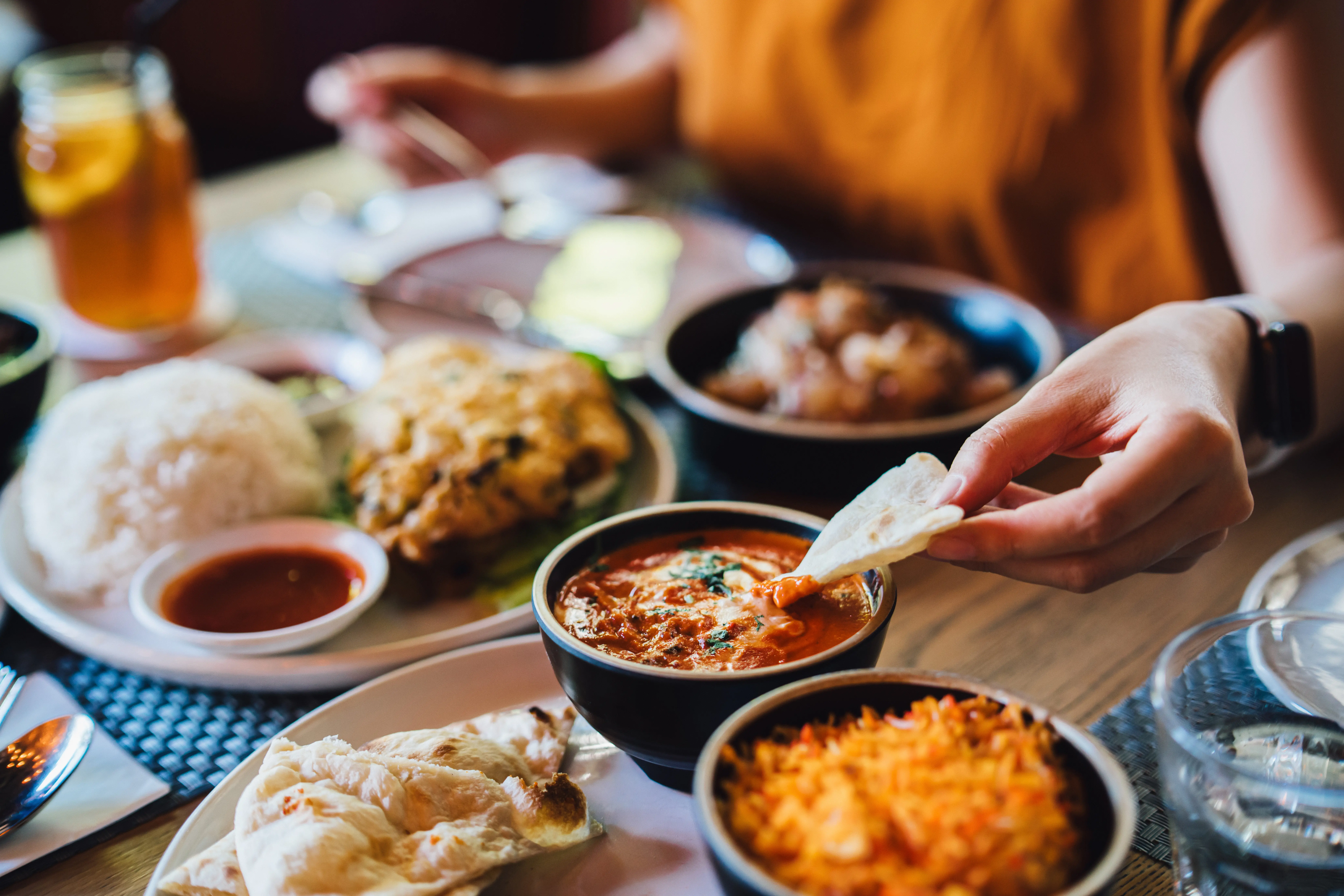 Closeup image of a woman eating assorted Thai food.