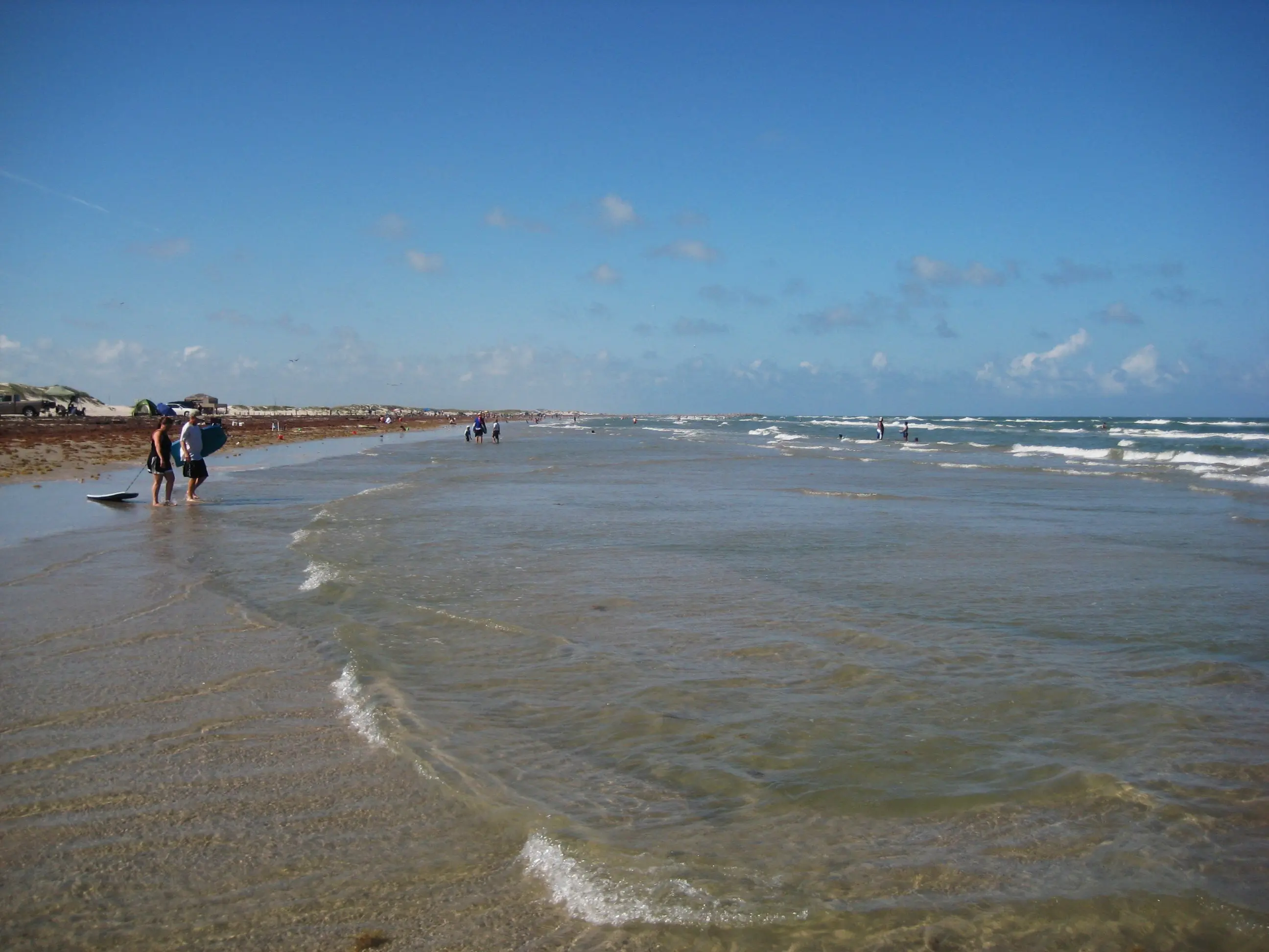 Image of beachgoers walking the shoreline at Mustang Island State Park
