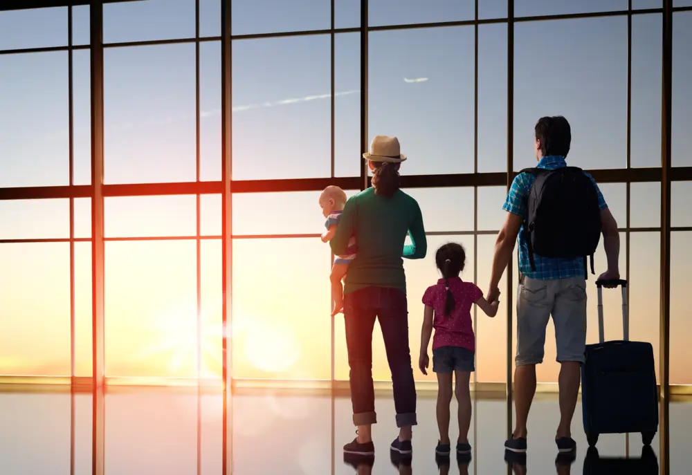 Family standing at airport window at sunset