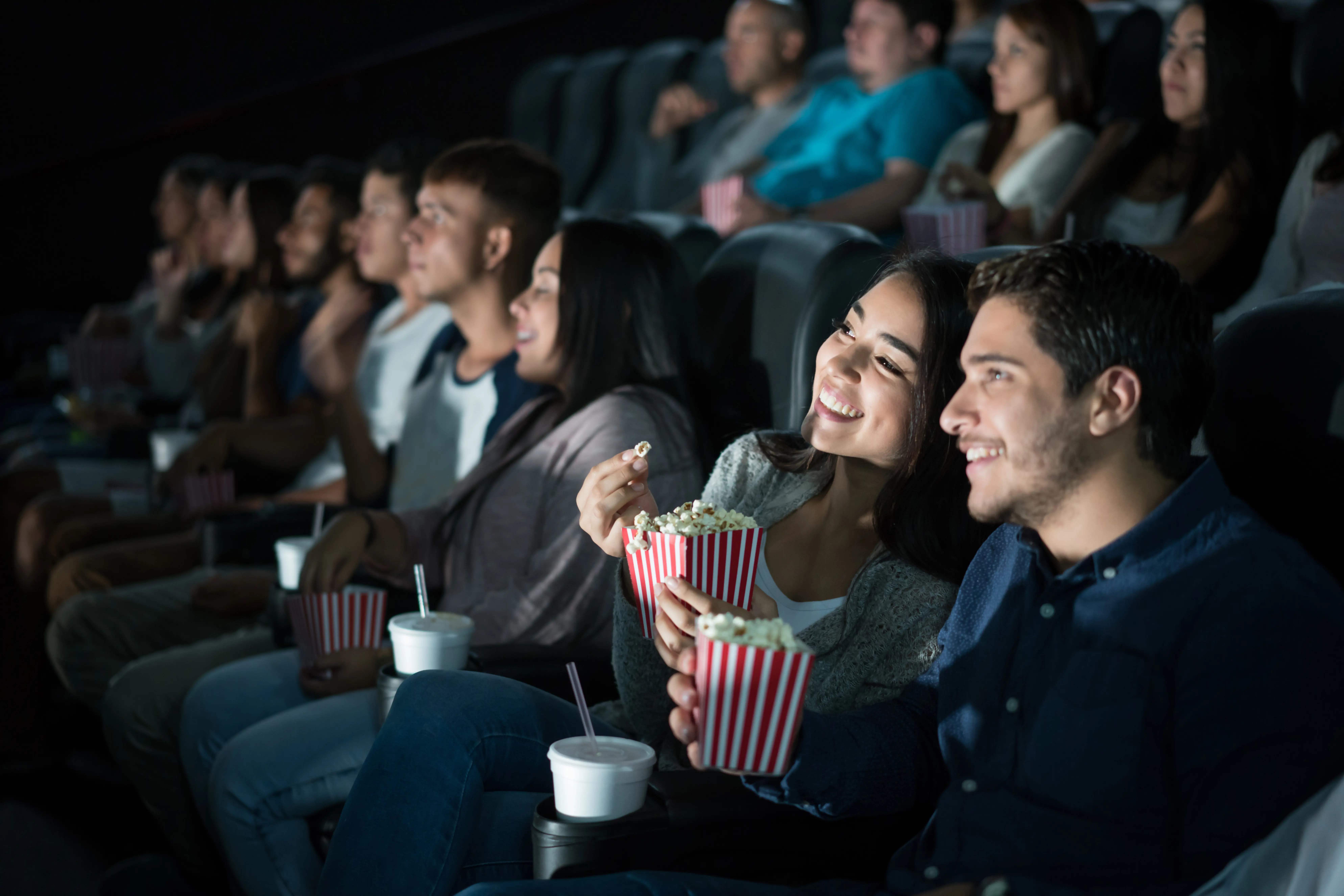 Movie theater patrons watching a movie and eating popcorn