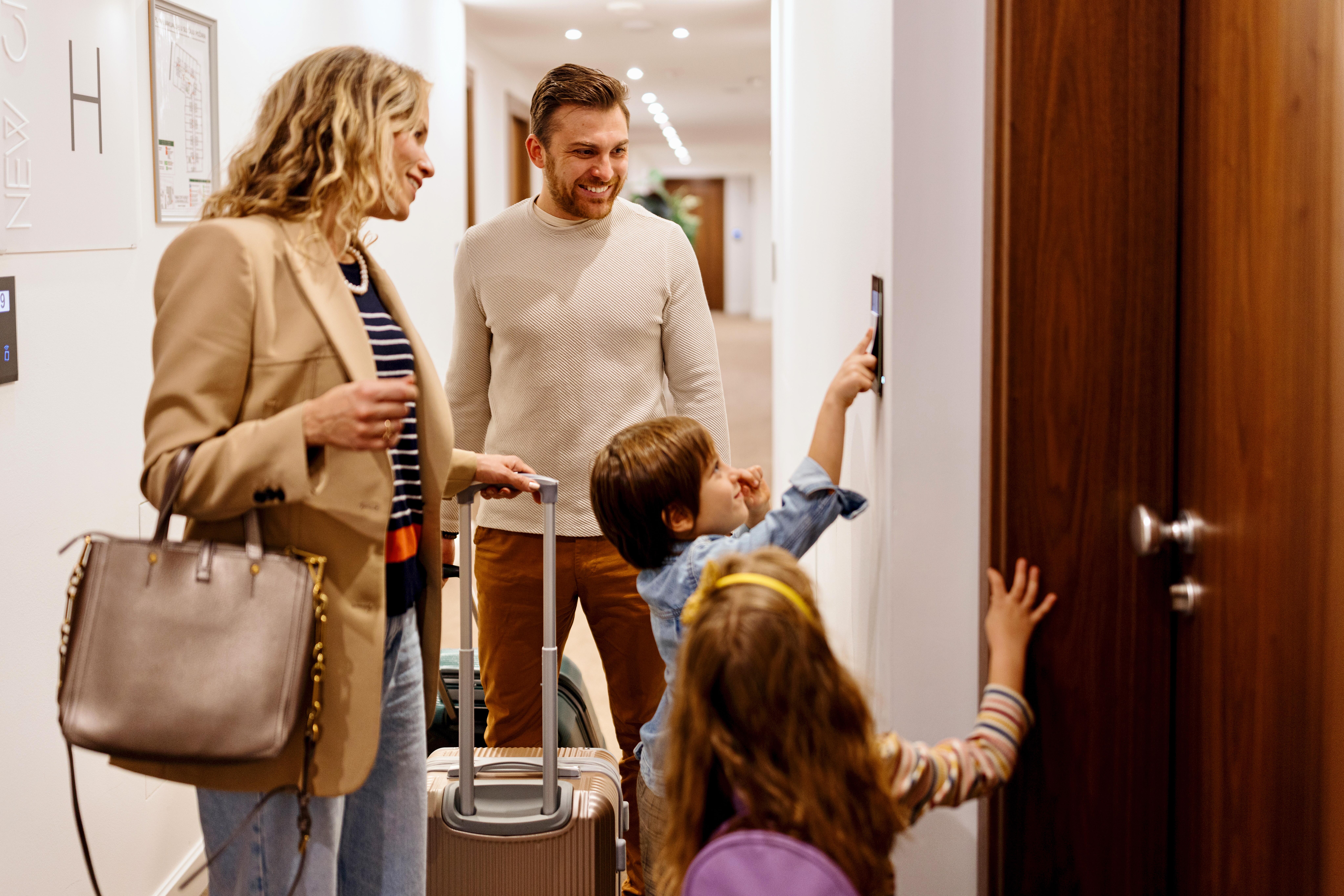 Family of four unlocking hotel room door with a key card