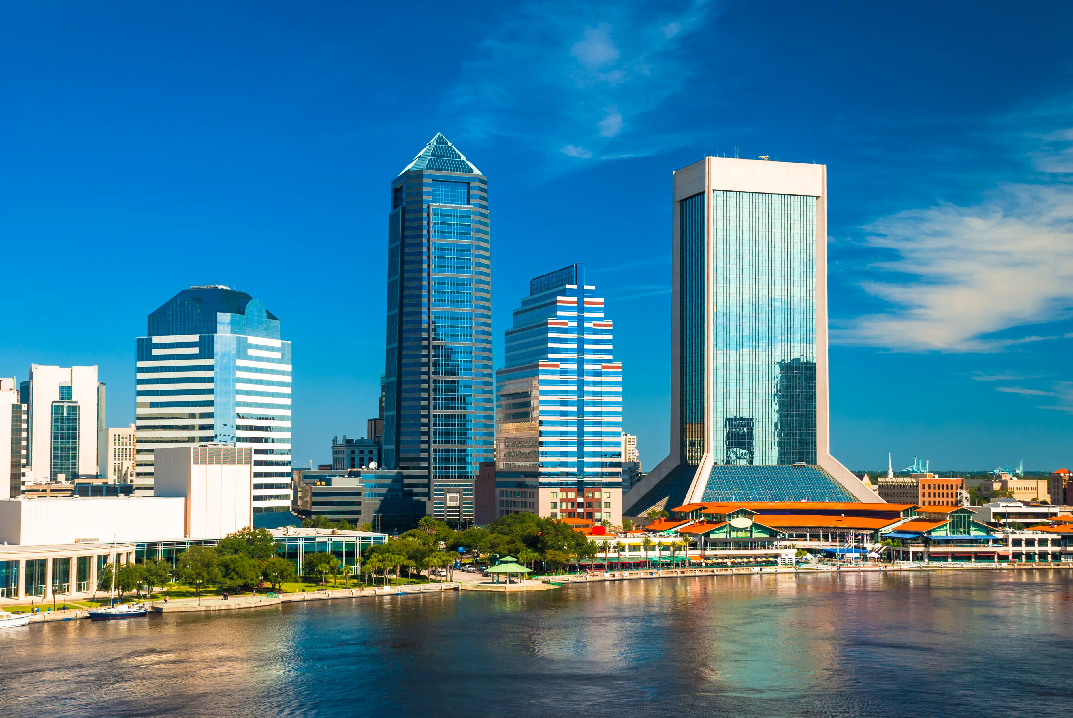 Downtown Jacksonville skyline aerial / elevated view with St. Johns River in the foreground and a deep blue sky with wispy clouds in the background
