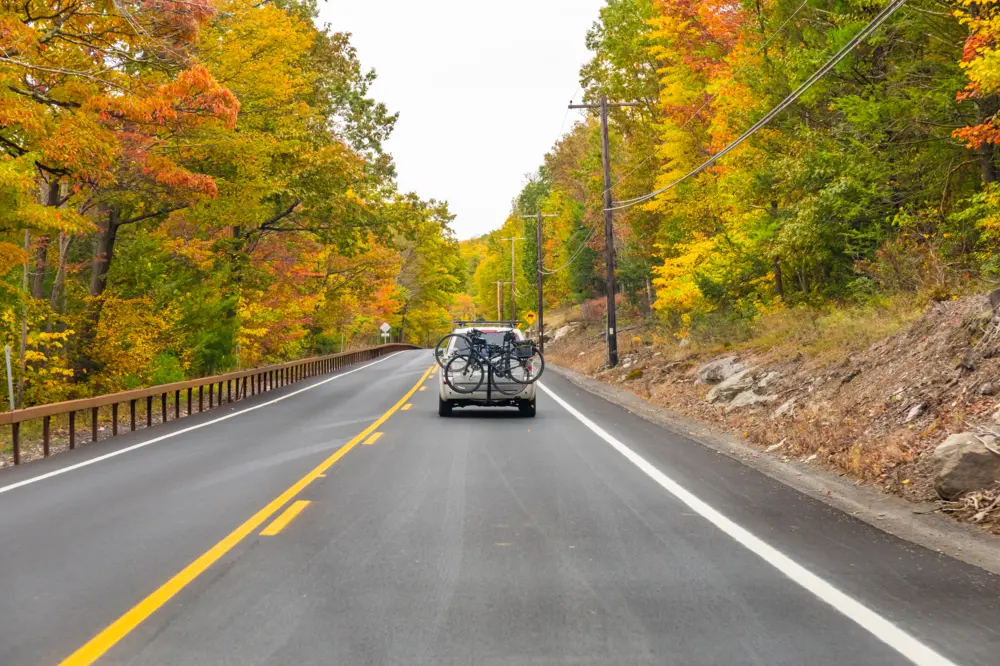 Car with bike rack driving on a road in Autumn