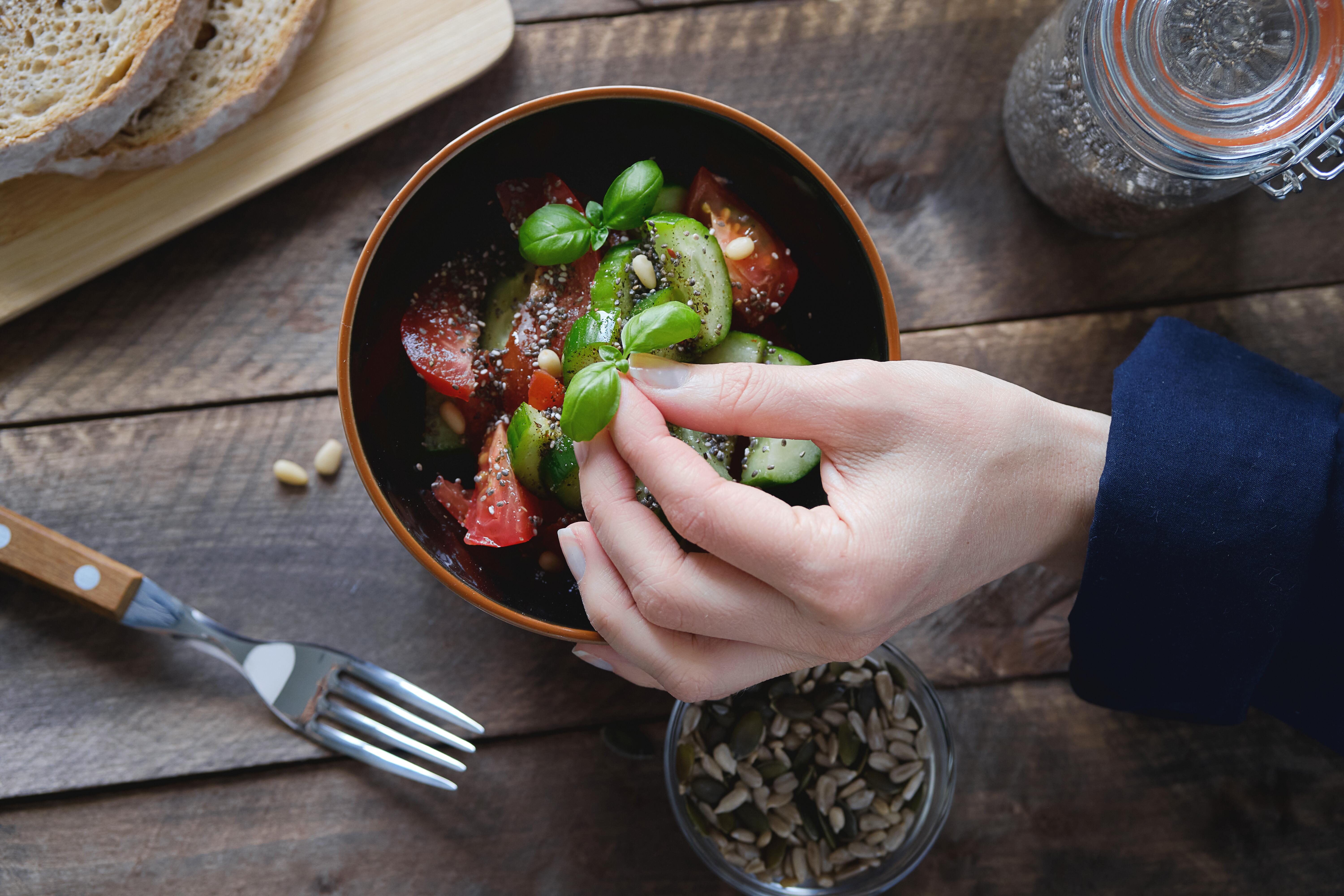 Overhead image of a vegetable dish being prepared on a wooden table.