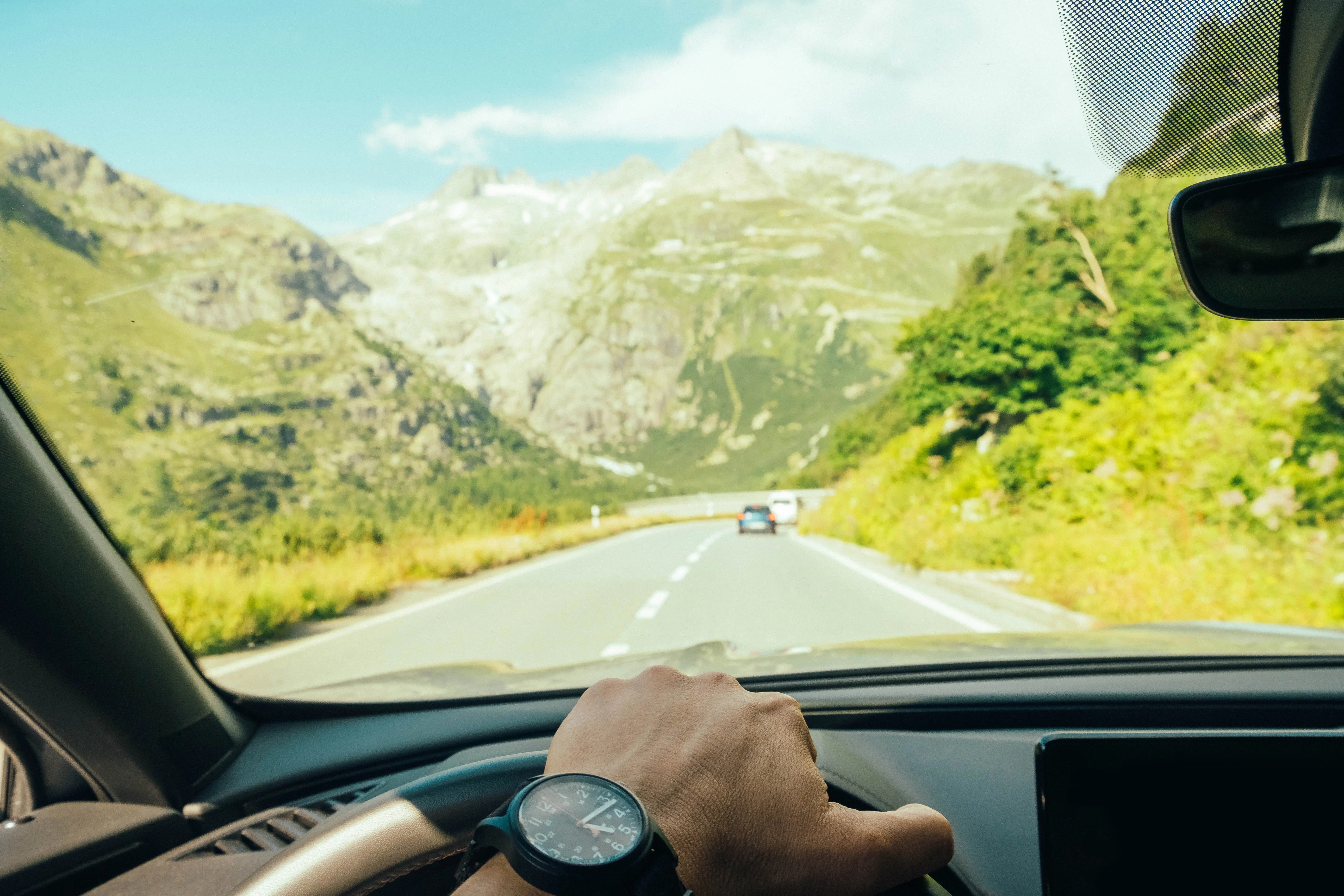 First person point of view image of a person driving in a scenic mountain landscape.
