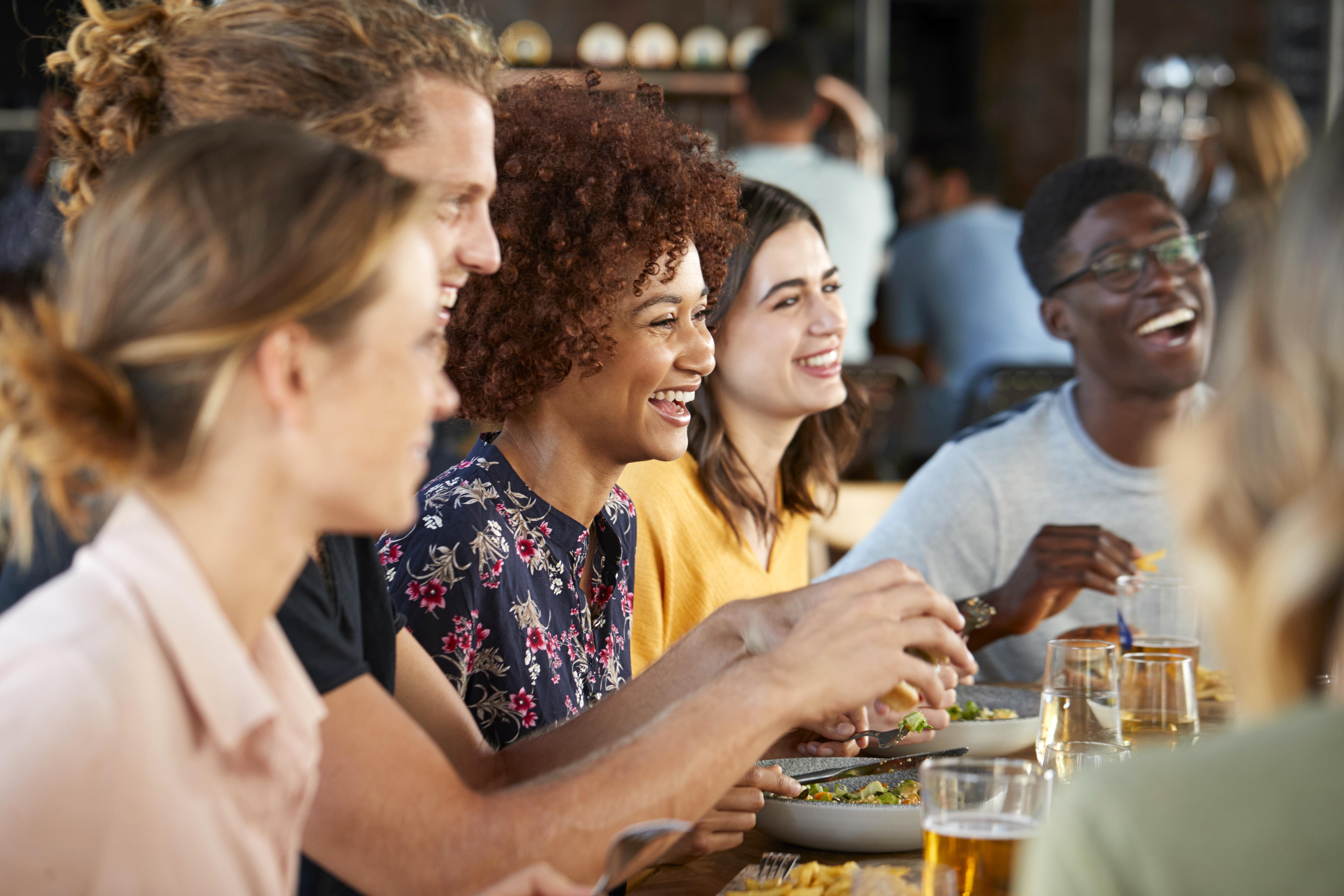 Young friends sitting around a table enjoying food