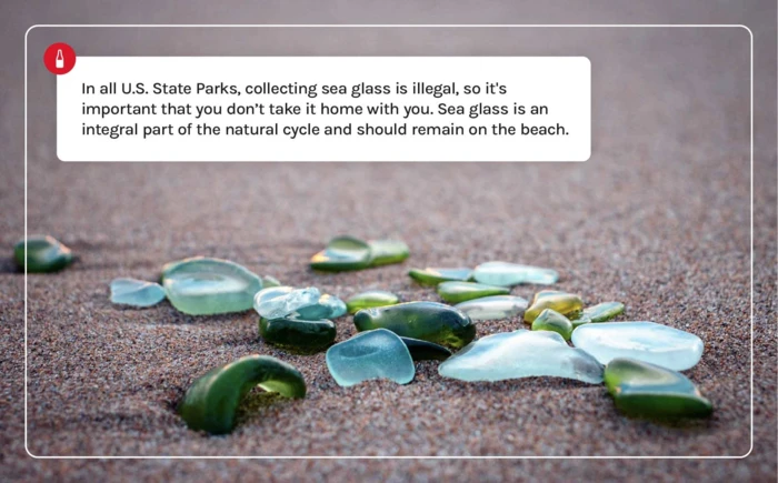 An array of sea glass laying on a sandy beach. 