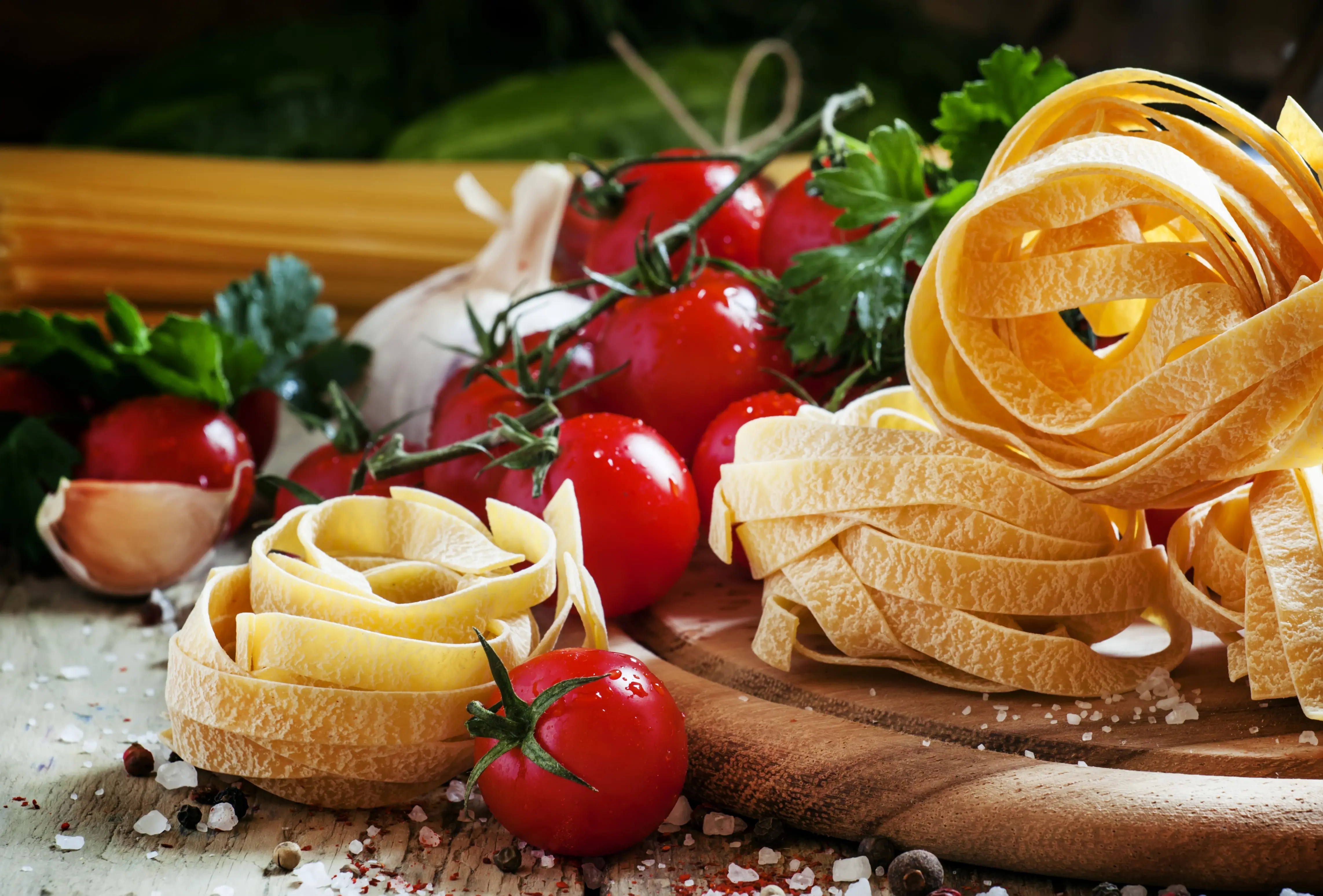Image of some fresh handmade pasta noodles sitting amongst some tomatoes.
