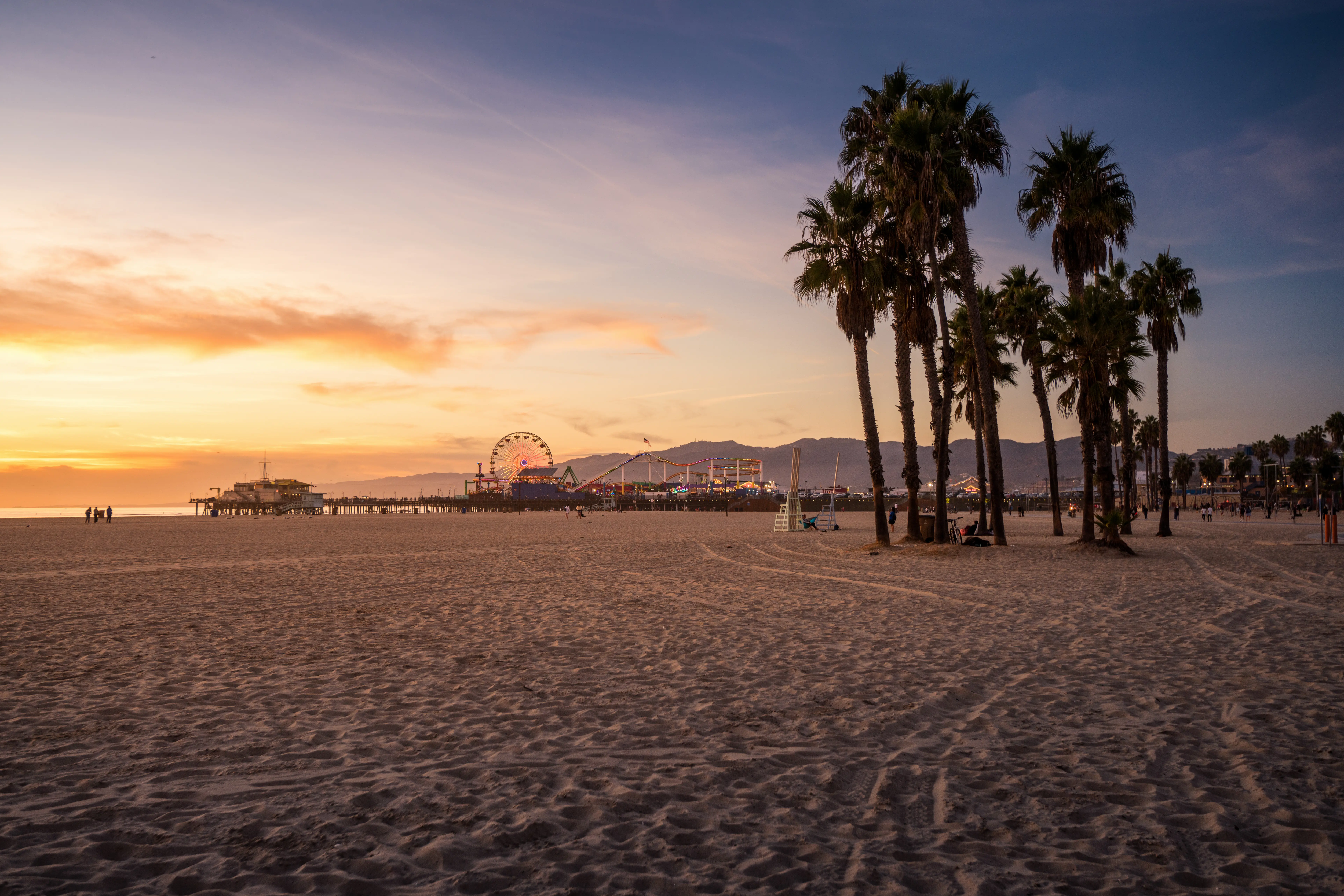 Outdoor image of Santa Monica beach at sunset, with the pier visible in the distance.