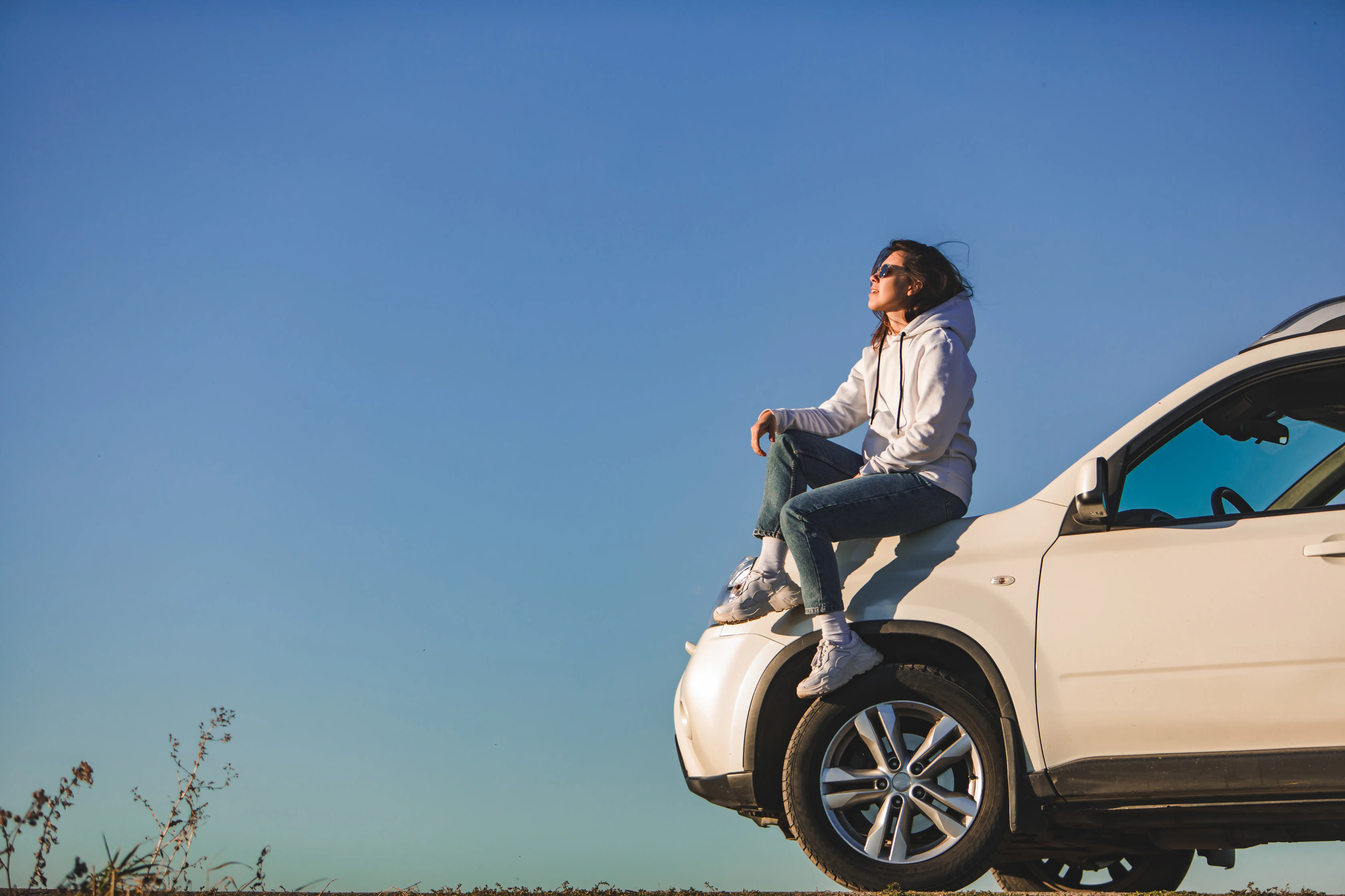 woman near white SUV car enjoying sunset