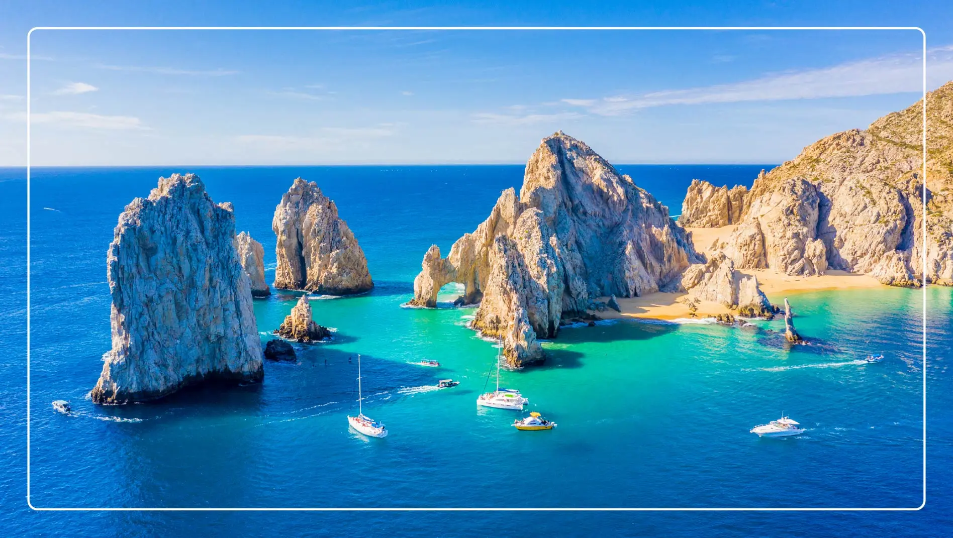Boats circle rock formations in the ocean in Los Cabos, Mexico.