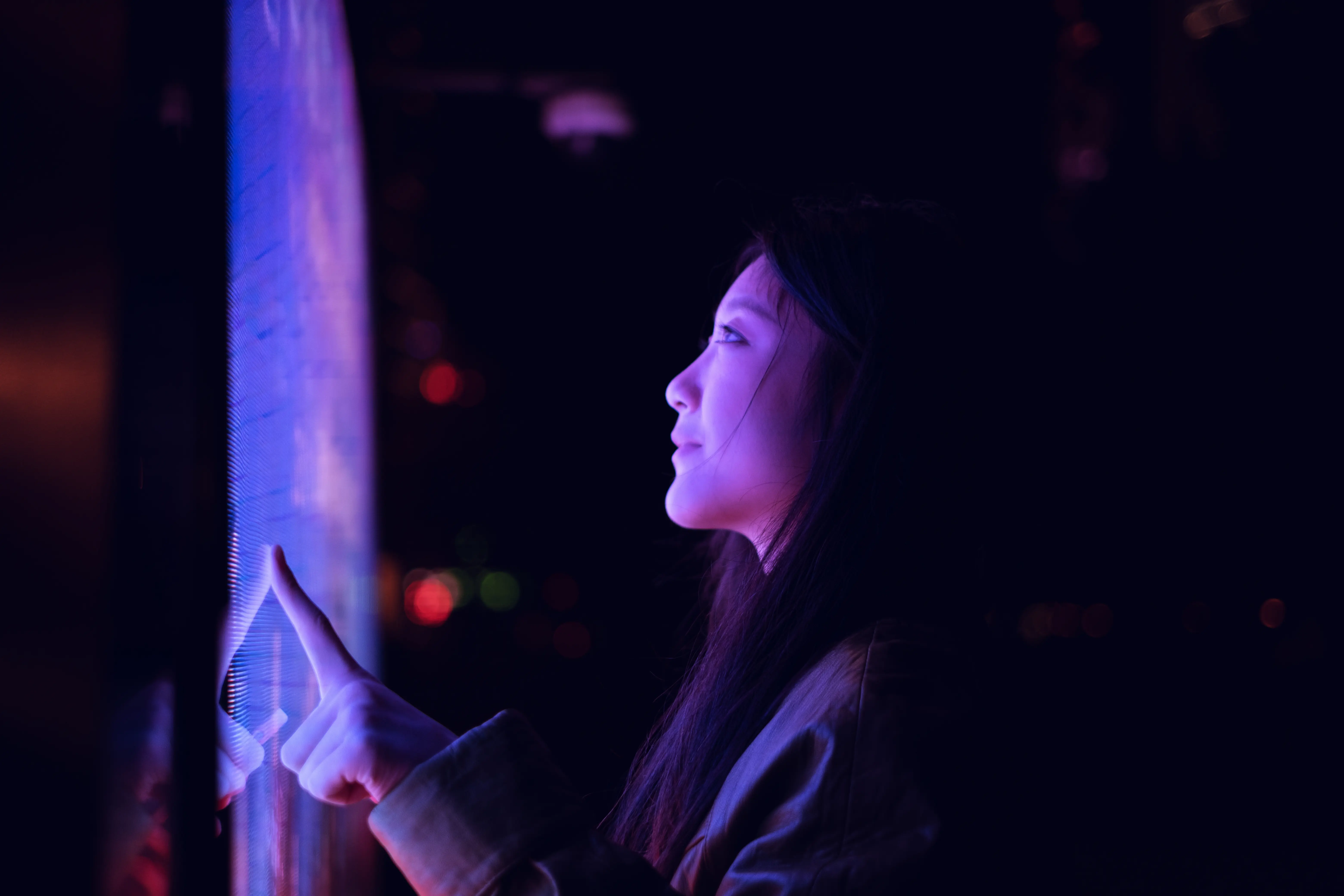 Image of a woman in a dark setting being illuminated by a pink LED panel.
