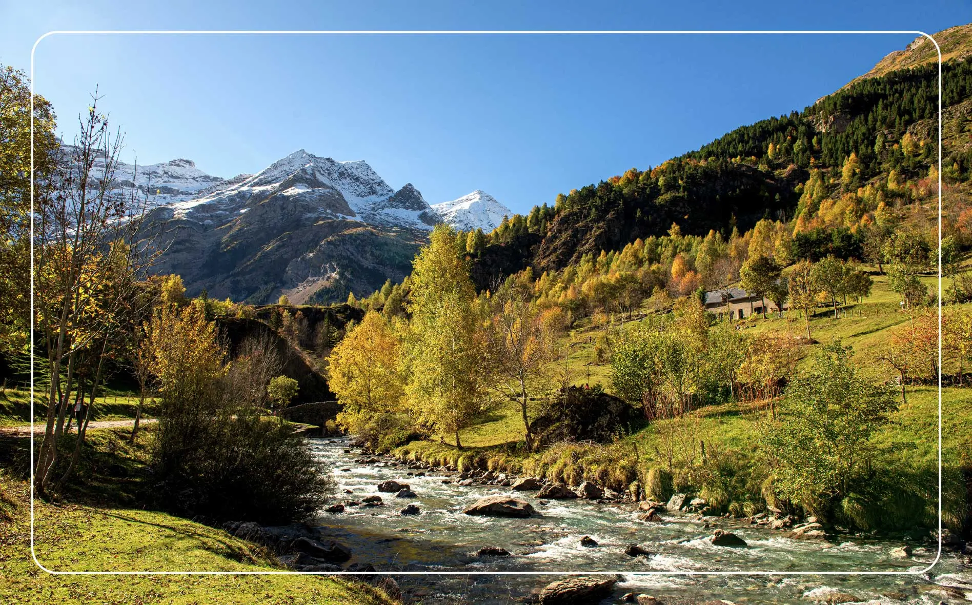 The picturesque trail leading to the Cirque de Gavarnie in the background is greenery and a waterway.