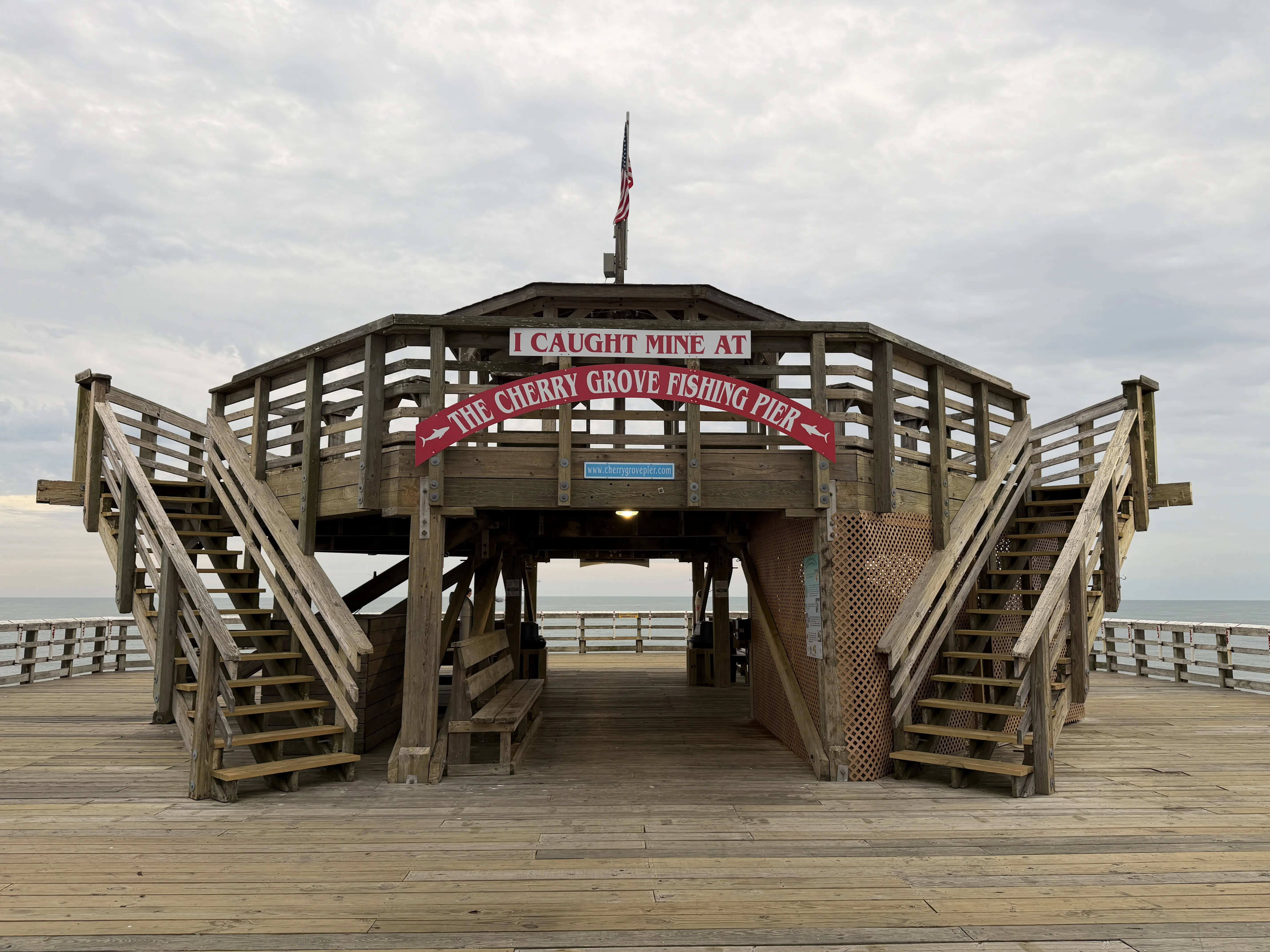 Wooden pier with sign on gazebo area saying "I caught mine at the Cherry Grove Pier."