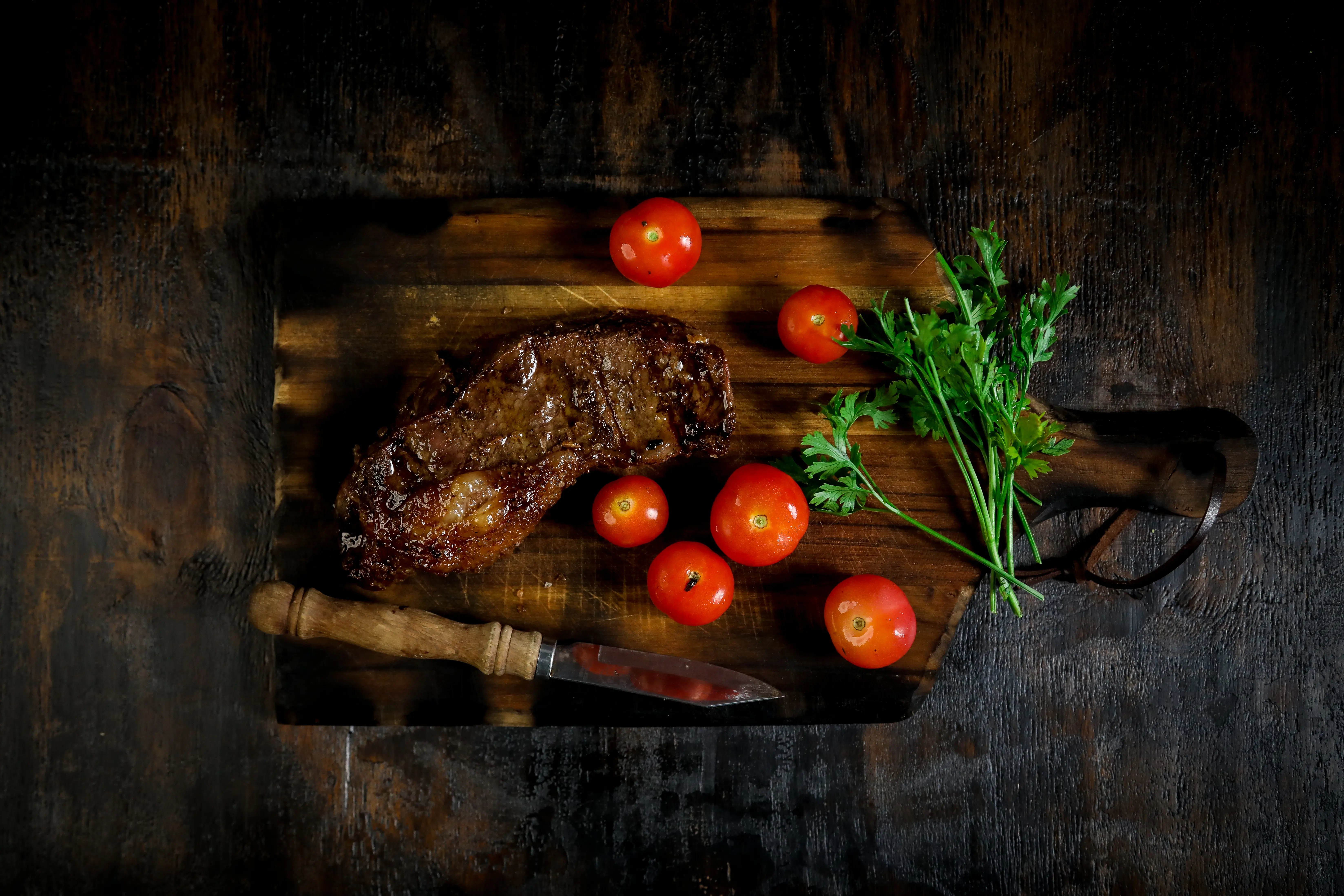 Overhead image of a steak and vegetables on a wooden cutting board.